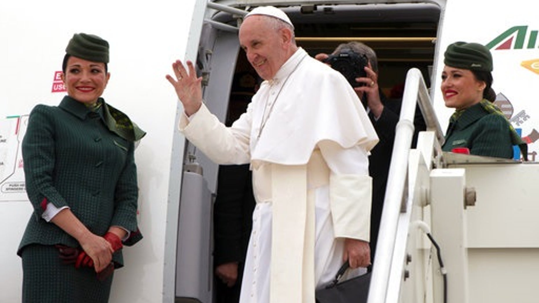 Pope Francis waves as he boards a plane on his way to Cairo, Egypt, at Rome's Fiumicino inernational airport, Friday, April 28, 2017. Francis is travelling to Egypt for a two-day trip aimed at presenting a united Christian-Muslim front that repudiates violence committed in God's name. (L'Osservatore Romano/Pool Photo via AP)