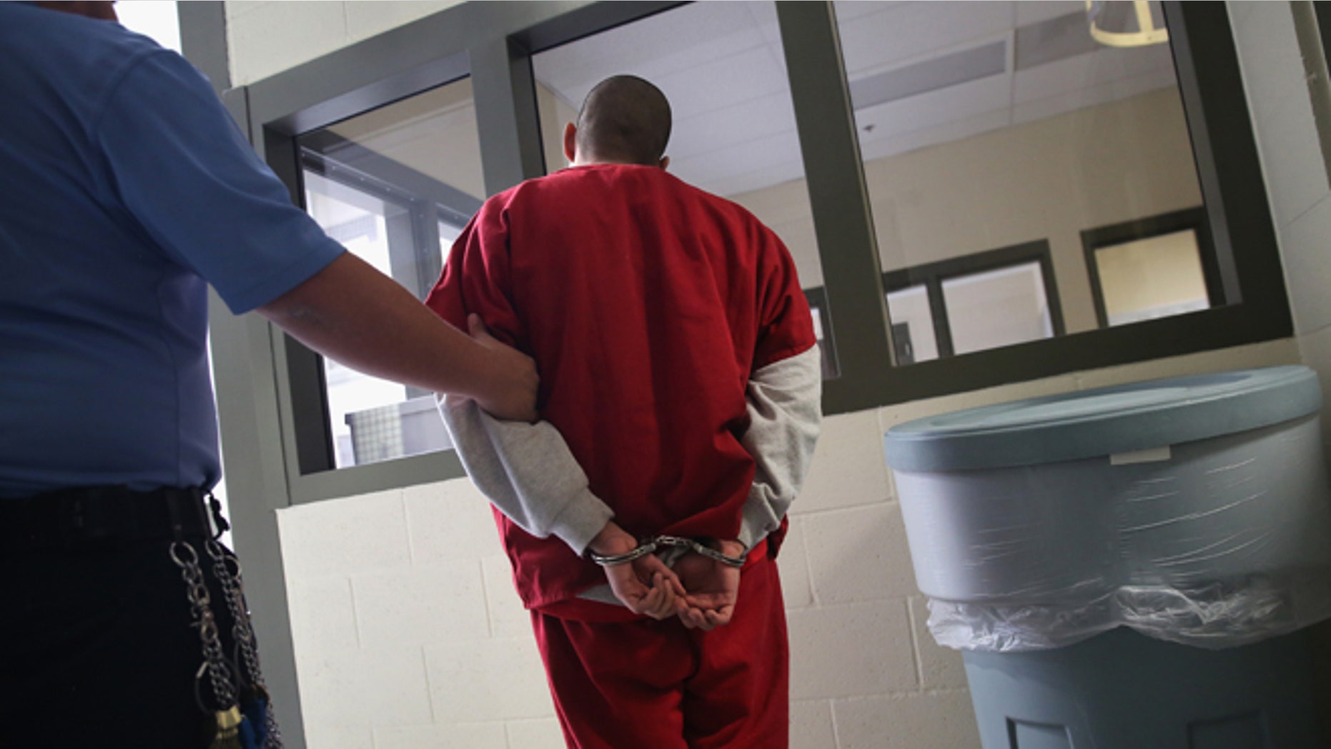 ADELANTO, CA - NOVEMBER 15: A guard escorts an immigrant detainee from his 'segregation cell' back into the general population at the Adelanto Detention Facility on November 15, 2013 in Adelanto, California. Most detainees in segregation cells are sent there for fighting with other immigrants, according to guards. The facility, the largest and newest Immigration and Customs Enforcement (ICE), detention center in California, houses an average of 1,100 immigrants in custody pending a decision in their immigration cases or awaiting deportation. The average stay for a detainee is 29 days. The facility is managed by the private GEO Group. ICE detains an average of 33,000 undocumented immigrants in more than 400 facilities nationwide. (Photo by John Moore/Getty Images)