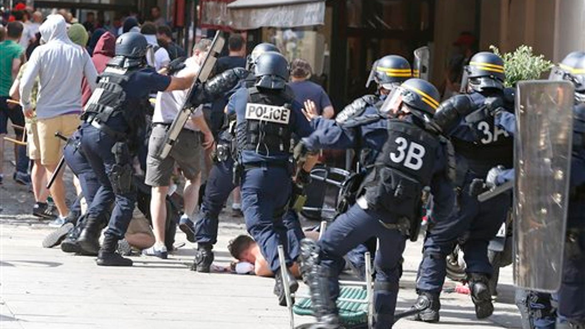 French police officers charge soccer supporters during clashes in downtown Marseille, France, Saturday, June 11, 2016. Riot police have thrown tear gas canisters at soccer fans Saturday in Marseille's Old Port in a third straight day of violence in the city. (AP Photo/Darko Bandic)