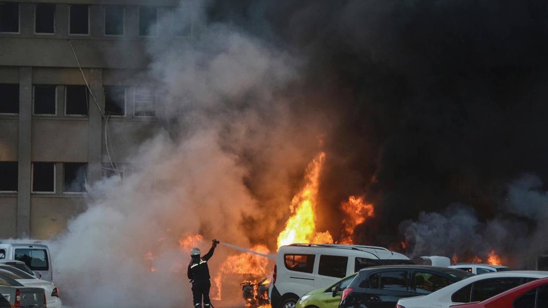 A police officer walks past by a fire after an explosion that killed people and wounded several others in southern city of Adana, Turkey, Thursday, Nov. 24, 2016.