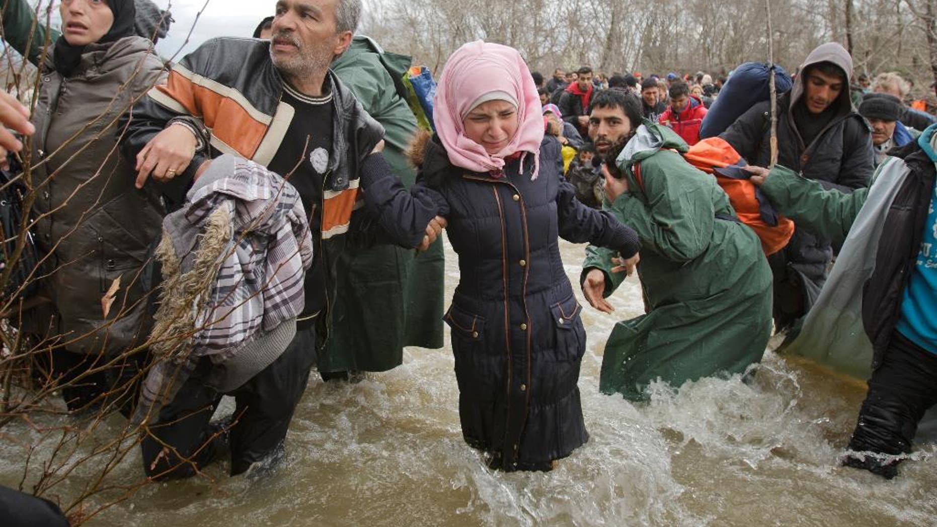 FILE - In this Monday, March 14, 2016 file photo, a woman cries as she crosses the river along with other migrants attempting to reach Macedonia on a route that would bypass the border fence, north of Idomeni, Greece. Eight asylum seekers are taking legal action against Macedonia for expelling them back to Greece after a chaotic mass border crossing earlier this year.
The migrant advocacy group ProAsyl said it helped the group file a complaint Monday, Sept. 12 with the Council of Europe's Court of Human Rights. (AP Photo/Vadim Ghirda, file)