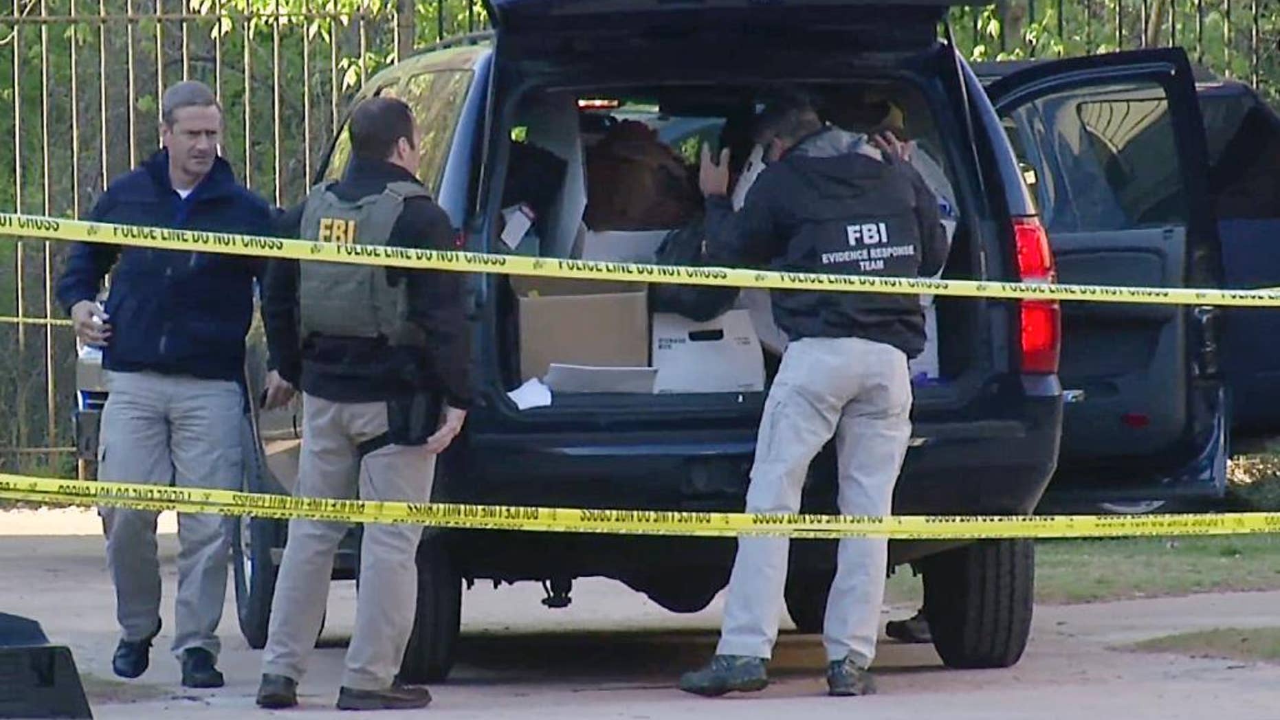 FILE - In this April 10, 2014, file photo taken from video, FBI agents collect evidence at an apartment complex in Atlanta, where federal agents rescued kidnap victim Frank Janssen, of Wake Forest, N.C. Kelvin Melton, a violent criminal described as a high-ranking member of the Bloods street gang goes on trial Monday, June 6, 2016, in North Carolina on a federal kidnapping charge after authorities say he helped orchestrate the abduction of Janssen, a prosecutor's father, from his prison cell. (AP Photo/Johnny Clark, File)