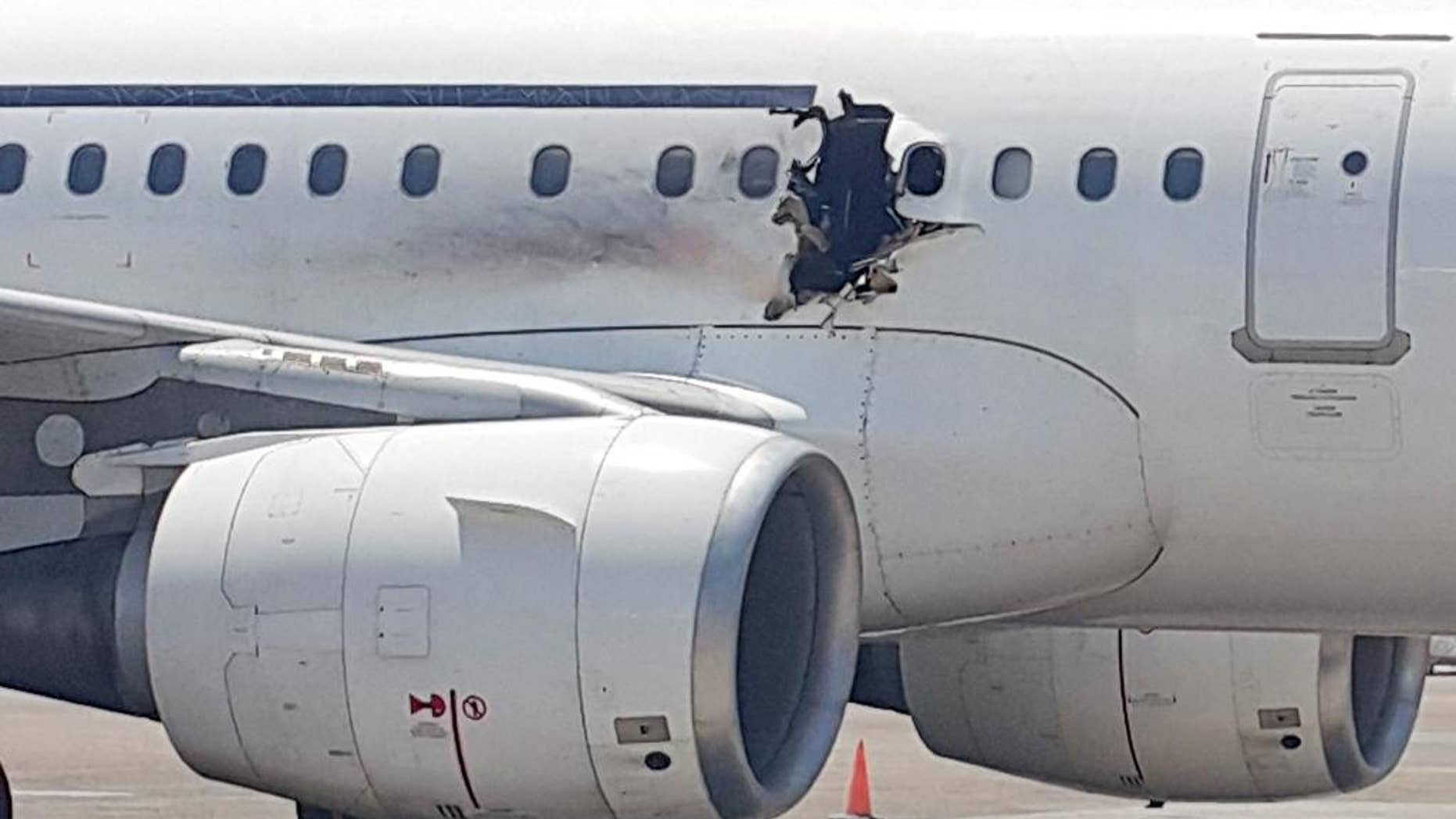 FILE - In this Tuesday, Feb. 2, 2016 file photo, of a hole in a plane operated by Daallo Airlines as it sits on the runway of the airport in Mogadishu, Somalia. A military court in the Somali capital has given life terms Monday, May 30, 2016 to two men convicted of masterminding the bombing in February of the airliner which made an emergency landing with a gaping hole in its fuselage. (AP Photo, File)