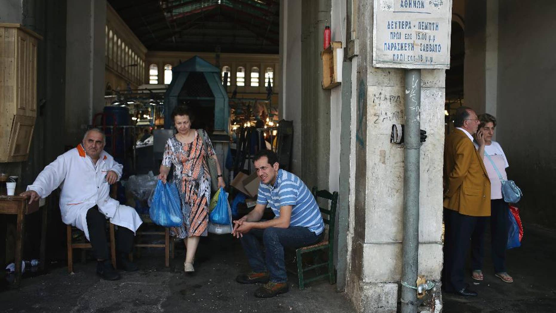 A woman carries bags as she leaves the Athens's central fish market as workers take a break, in Athens, Wednesday, May 10, 2017. Greece has been surviving on bailout loans since 2010 in return for harsh spending cuts and tax increases that have put nearly a quarter of the workforce out of work and seen more than a third of the population living or at risk of poverty. (AP Photo/Petros Giannakouris)