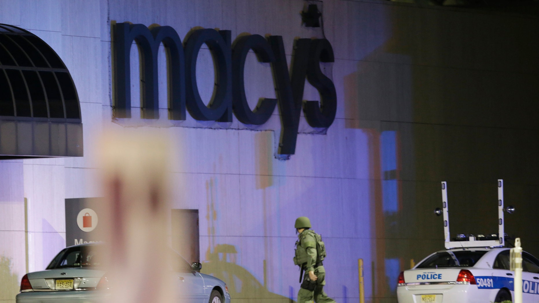 An official wearing tactical gear walks outside of Garden State Plaza Mall following reports of a shooter, Monday, Nov. 4, 2013, in Paramus, N.J. Hundreds of law enforcement officers converged on the mall Monday night after witnesses said multiple shots were fired there. (AP Photo/Julio Cortez)