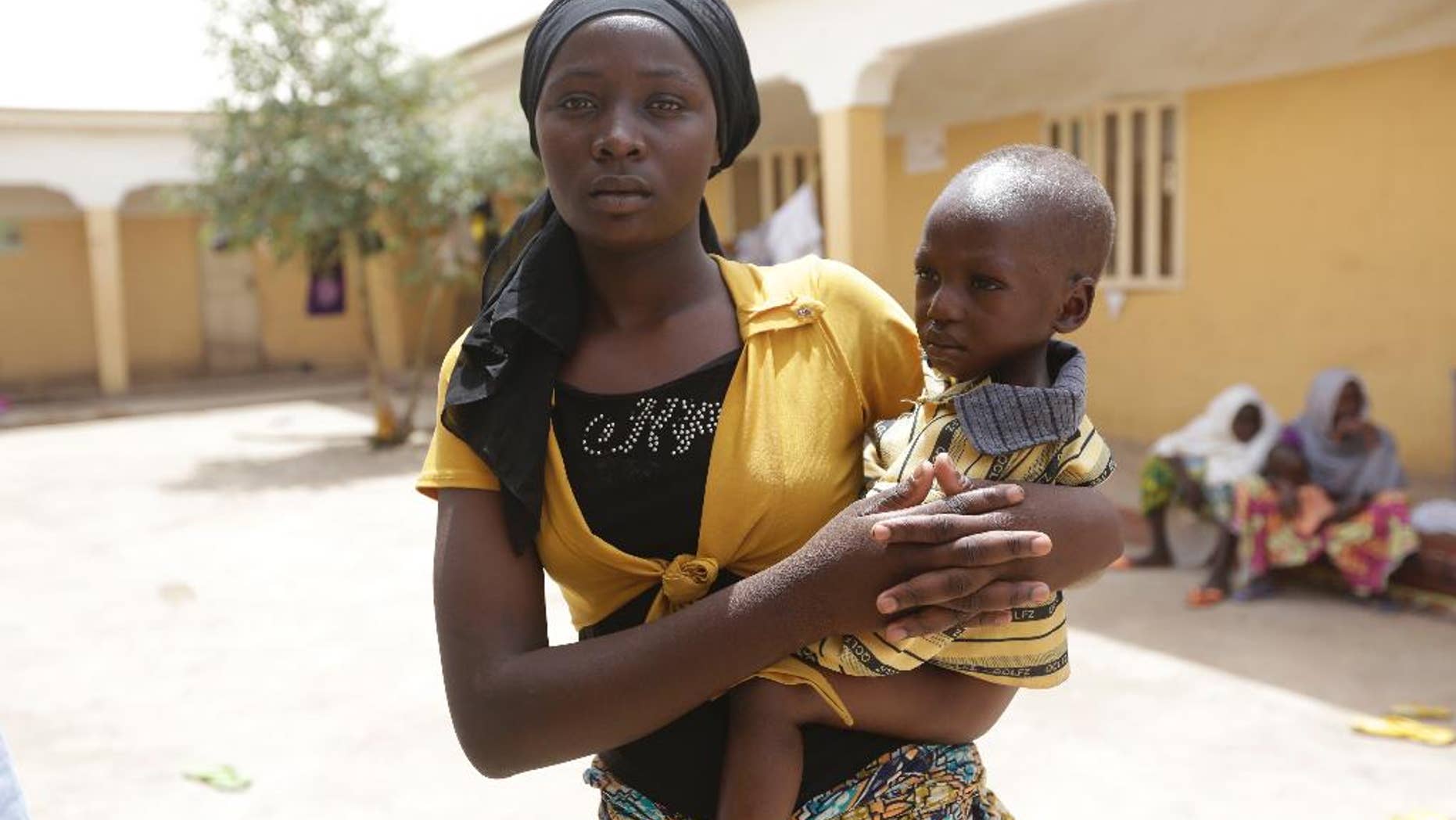 FILE - In this Monday, May 4, 2015 file photo, Binta Ibrahim holds an unidentified child after she described told how at 16 she rescued three children aged between 2 and 4, cared for them during a year of captivity under Boko Haram and brought them to the safety of the refugee camp in Yola. All 275 women, girls and children rescued from Boko Haram and taken to the safety of a northeast Nigerian refugee camp have been taken into military custody amid suspicions that some are aiding the Islamic extremists, a camp official and a Nigerian military intelligence officer said Wednesday May 20, 2015. (AP Photo/Sunday Alamba, File)