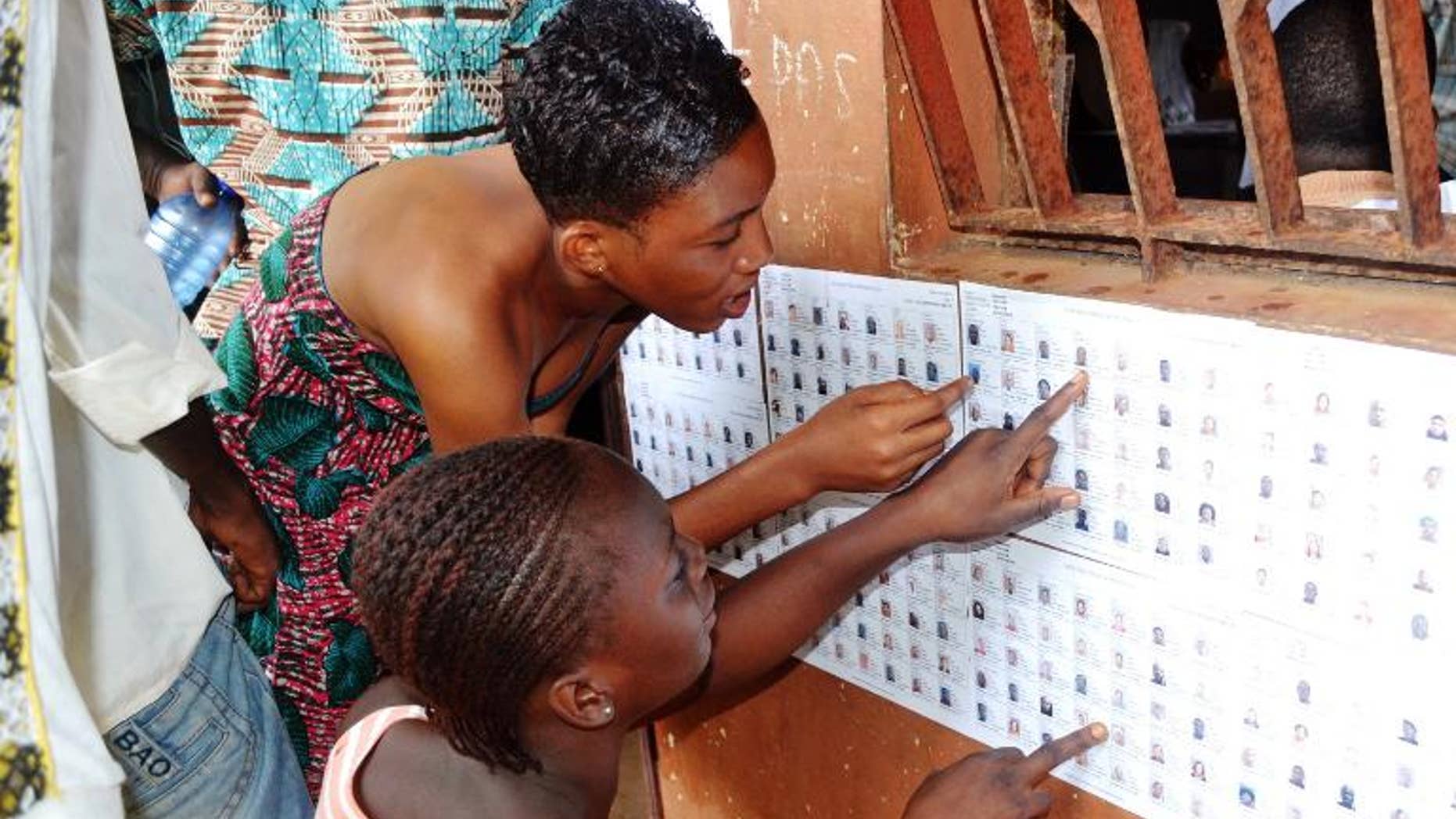 Guinean women search for their names on the registered voters' list at a polling station in Conakry on September 28, 2013