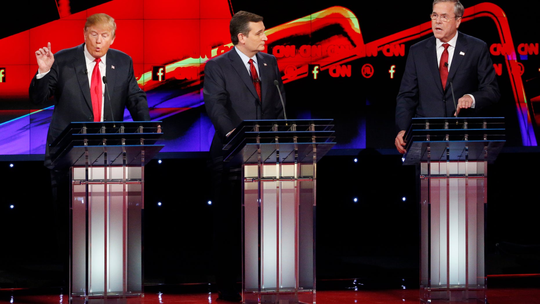 Donald Trump, a la izquierda, y Jeb Bush, a la derecha, hablan ante la mirada de Ted Cruz durante el debate republicano de CNN en el hotel y casino Venetian de Las Vegas, el martes 15 de diciembre de 2015 en Las Vegas. (AP Foto/John Locher)