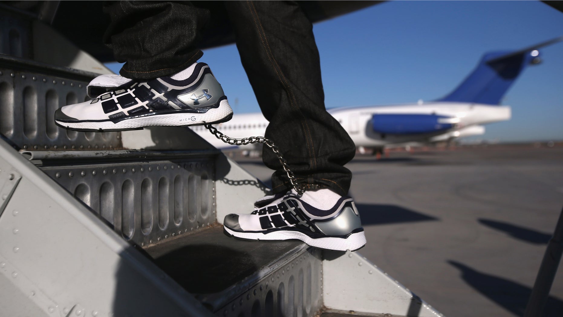 MESA, AZ - FEBRUARY 28: A Honduran immigration detainee, his feet shackled and shoes laceless as a security precaution, boards a deportation flight to San Pedro Sula, Honduras on February 28, 2013 in Mesa, Arizona. U.S. Immigration and Customs Enforcement (ICE), operates 4-5 flights per week from Mesa to Central America, deporting hundreds of undocumented immigrants detained in western states of the U.S. With the possibility of federal budget sequestration, Most detainees typically remain in custody for several weeks before they are deported to their home country, while others remain for longer periods while their immigration cases work through the courts. (Photo by John Moore/Getty Images)