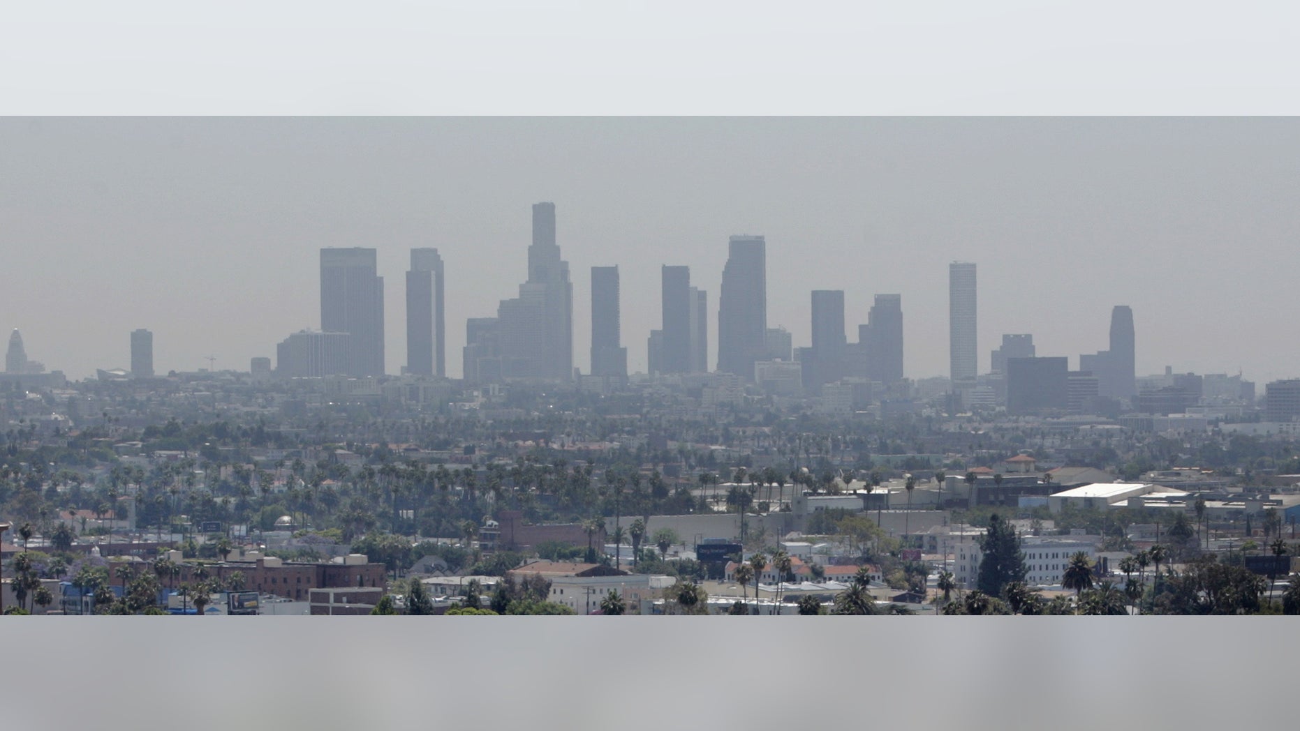 The skyline of downtown Los Angeles through a layer of smog is seen in the distance from a rooftop in Hollywood, California, May 31, 2006. (REUTERS/Fred Prouser/Files)