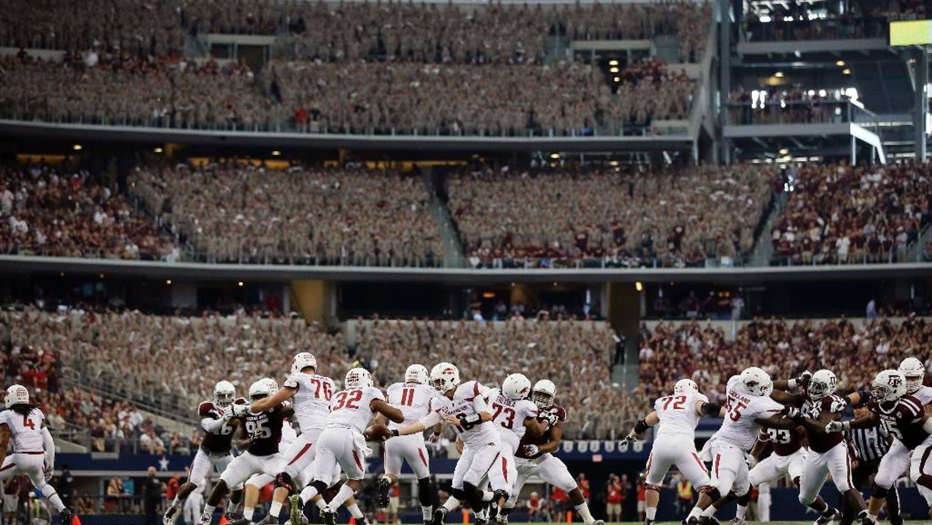 Arkansas quarterback Brandon Allen (10) hands off to running back Jonathan Williams (32) in the first half of an NCAA college football game against Texas A&M, Saturday, Sept. 27, 2014, in Arlington, Texas. The Aggie Corps. of Cadets fill the stadium seats at rear during the game. (AP Photo/Tony Gutierrez)