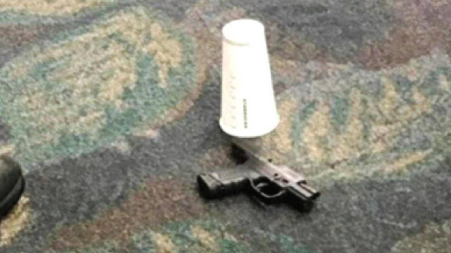 This photo taken Friday, Jan. 6, 2017 by passenger Mark Lea and released by Lea Sunday, Jan. 8 shows a handgun which was used by Iraq war veteran Esteban Santiago when he killed five people is seen on the floor at the scene of the attack at the Fort Lauderdale airport in Florida. In a post-9/11 world, American airports have taken all sorts of steps to keep travelers safe. But significant vulnerabilities remain. The attack that killed five people Friday at the Florida airport raised concerns about how to further protect travelers and what place firearms have in U.S. airports. (Mark Lea via AP)