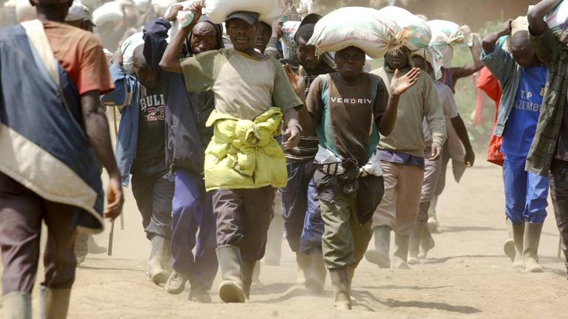 Men carry bags of cassiterite, coltan and computers, and manganese on May 28, 2013 from the Mudere mine, near Rubaya, some 9 kms from the eastern Democratic Republic of Congo city of Goma.