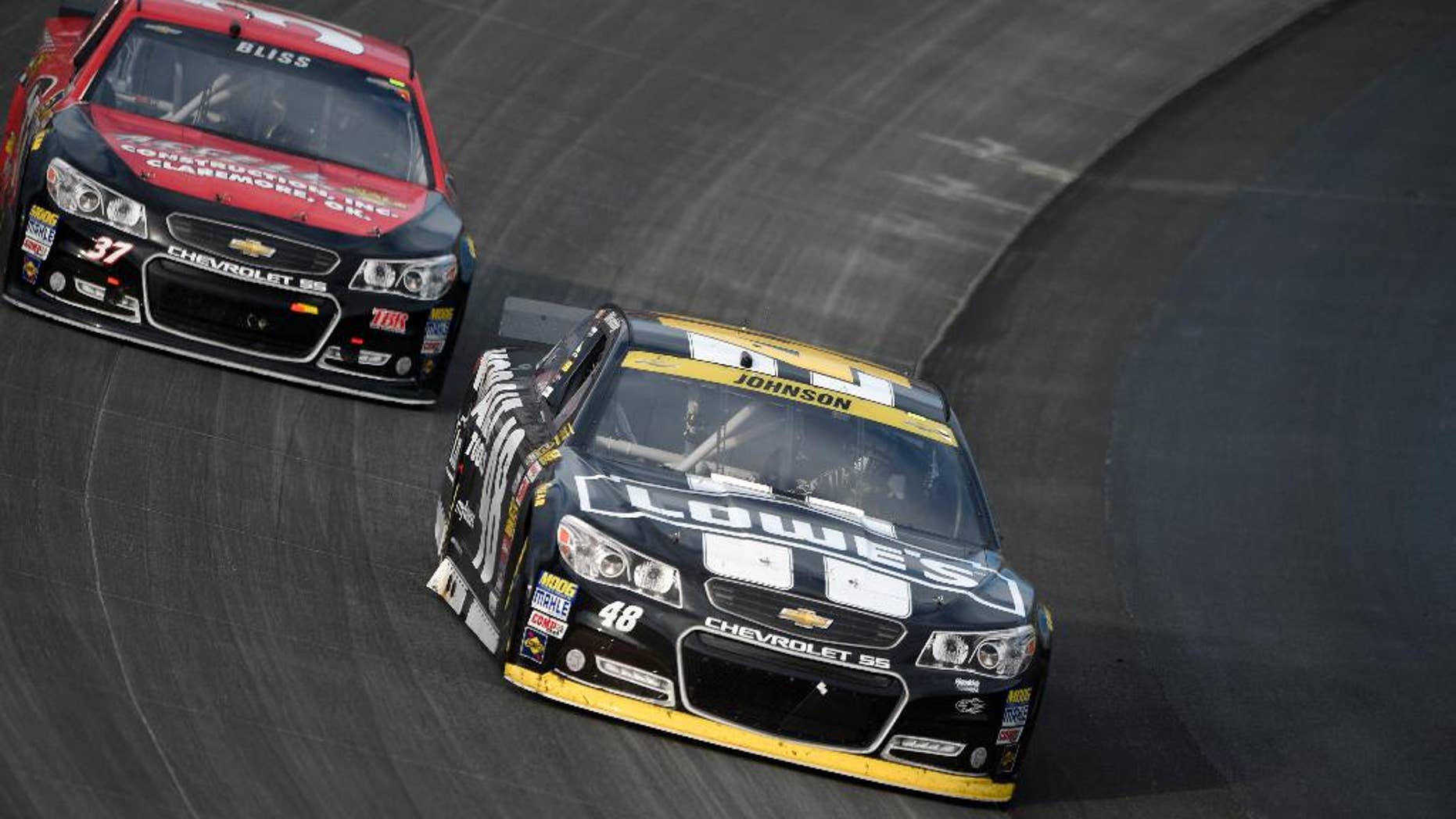 Jimmie Johnson, front, races in front of Mike Bliss during the NASCAR Sprint Cup series auto race, Sunday, Sept. 28, 2014, at Dover International Speedway in Dover, Del. Johnson finished the race in third place. (AP Photo/Nick Wass)