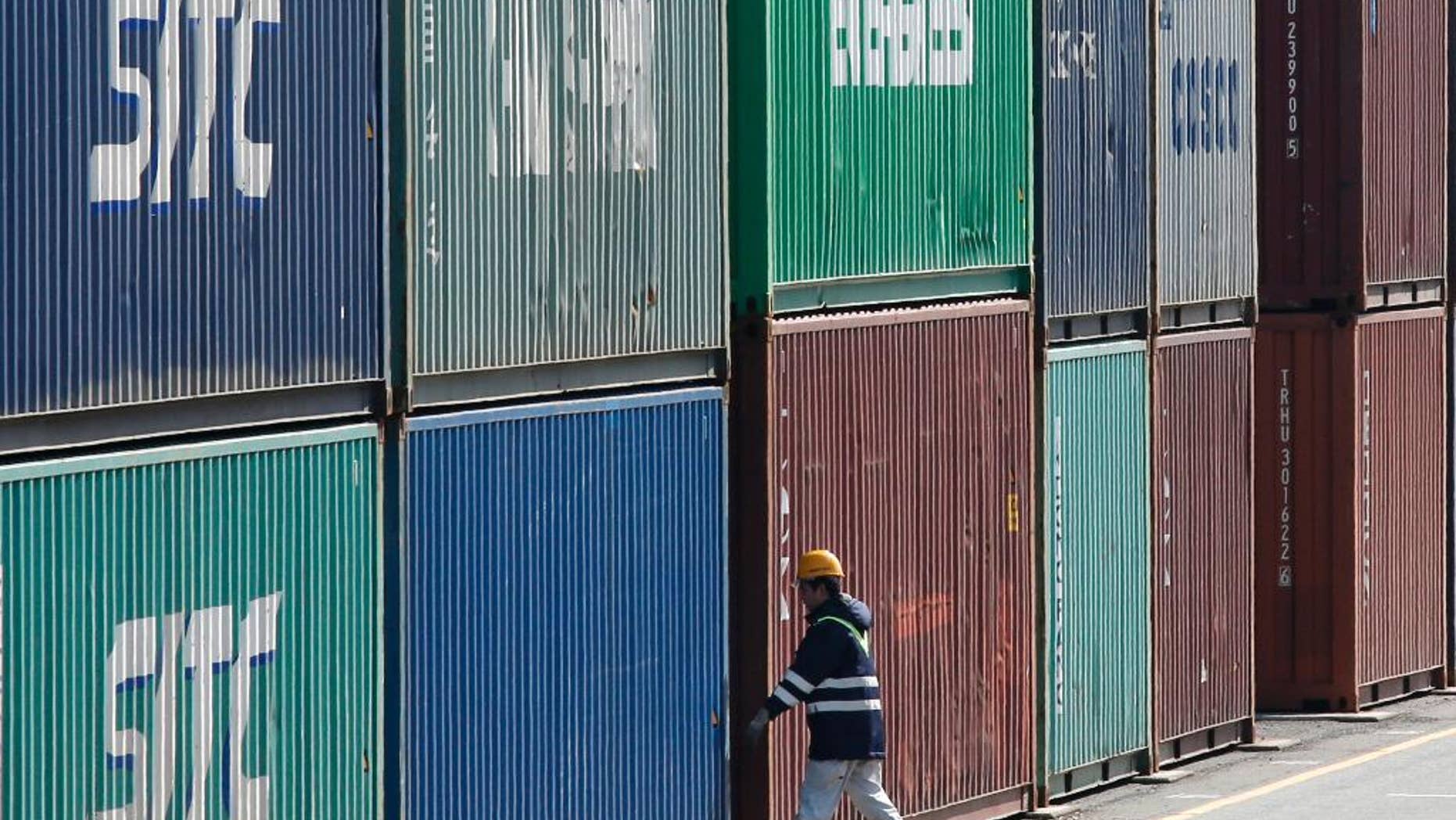 In this Feb. 18, 2016 photo, a port worker walks through the piled containers in Tokyo. Japan posted a trade surplus of 513.5 billion yen ($5.1 billion) in July, though exports sank 14 percent from a year earlier as the yen surged against the dollar, the government reported Thursday, Aug. 18, 2016. (AP Photo/Shuji Kajiyama)