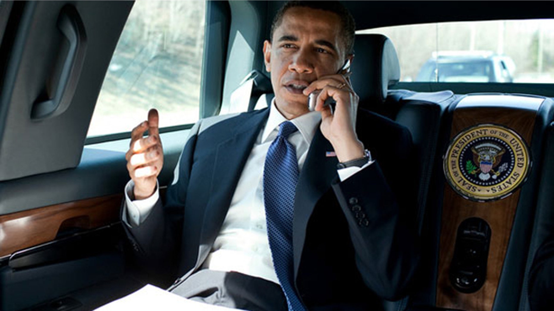 President Barack Obama speaks on an unidentified flip phone in the presidential limousine in northern Virginia in March 2010.