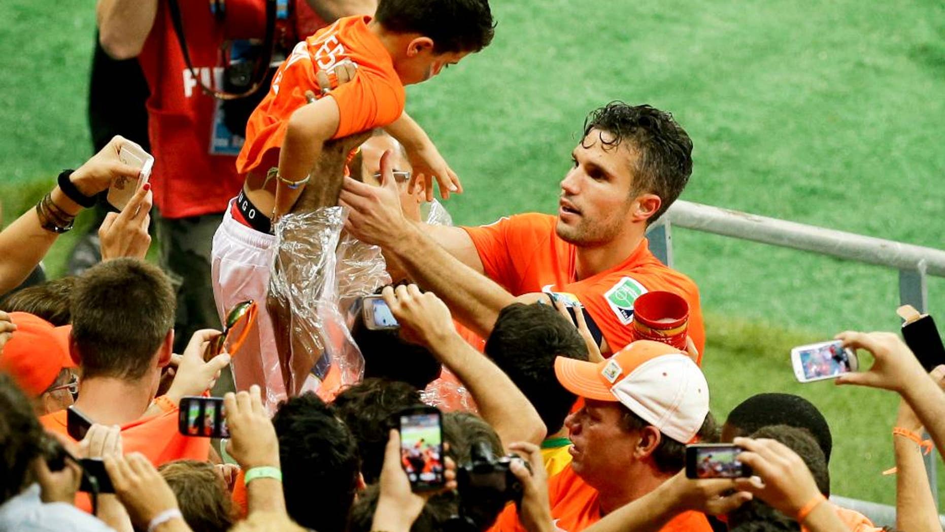 Netherlands' Robin van Persie holds a boy as he celebrates with fans after winning the World Cup quarterfinal soccer match between the Netherlands and Costa Rica at the Arena Fonte Nova in Salvador, Brazil, Saturday, July 5, 2014. Netherlands beat Costa Rica 4-3 on penalties to reach semifinals of the World Cup. (AP Photo/Themba Hadebe)