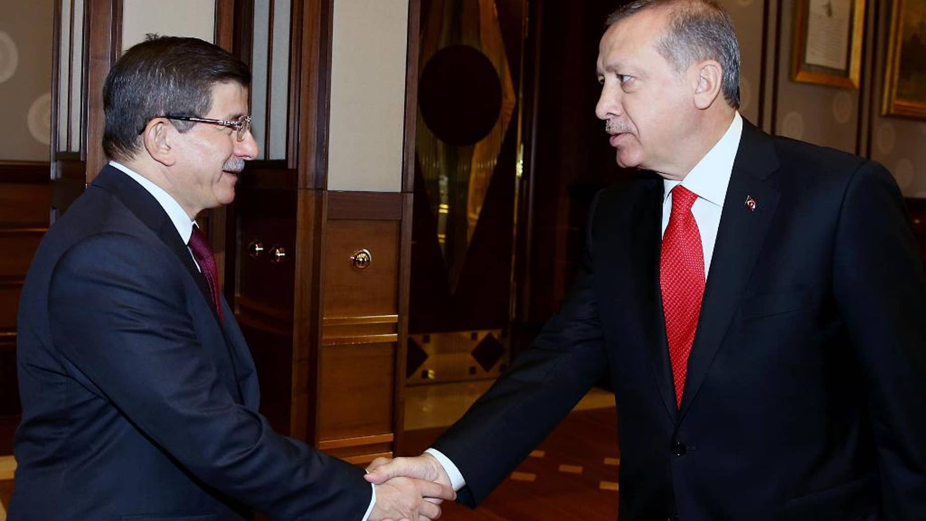 Turkey's President Recep Tayyip Erdogan, right, shakes hands with Prime Minister Ahmet Davutoglu before a meeting in Ankara, Turkey, Tuesday, Aug. 25, 2015. Erdogan on Tuesday appointed Davutoglu to form an interim government that will lead the country into a new election, likely to take place on Nov. 1. Erdogan formally called for a new election late on Monday, following an inconclusive vote in June, and the collapse of coalition-building efforts.(Presidential Press Service via AP, Pool)