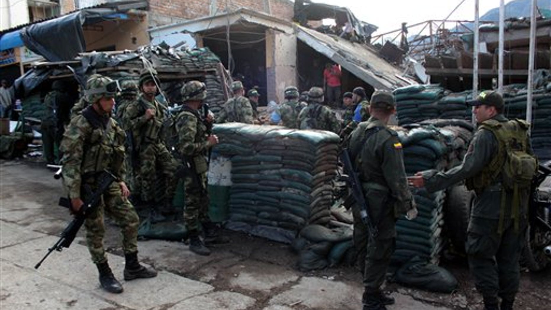 Police officers and soldiers stand in front of the destroyed police station of Inza, in Colombia's southern Cauca state, Saturday, Dec. 7, 2013. The Colombian Army said that five members of the military, two civilians and a police officer were killed after rebels of the Revolutionary Armed Forces of Colombia, FARC, threw artisanal mortar at the post from a truck, destroying that and several other buildings. (AP Photo/Juan Bautista Diaz)