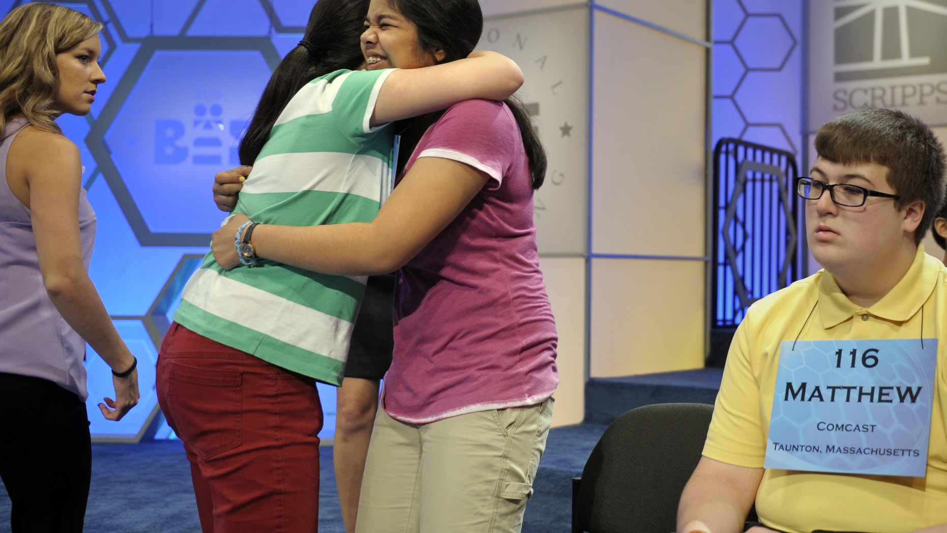 Katharine Wang, 11, of Beijing, China, second from left, hugs Amber Born, 14 of Marblehead, Massachusetts at the start of the semifinal round of the Scripps National Spelling Bee in Oxon Hill, Md., Thursday, May 30, 2013. Matthew Donohue of Kingston, Mass. is at right. (AP Photo/Cliff Owen)