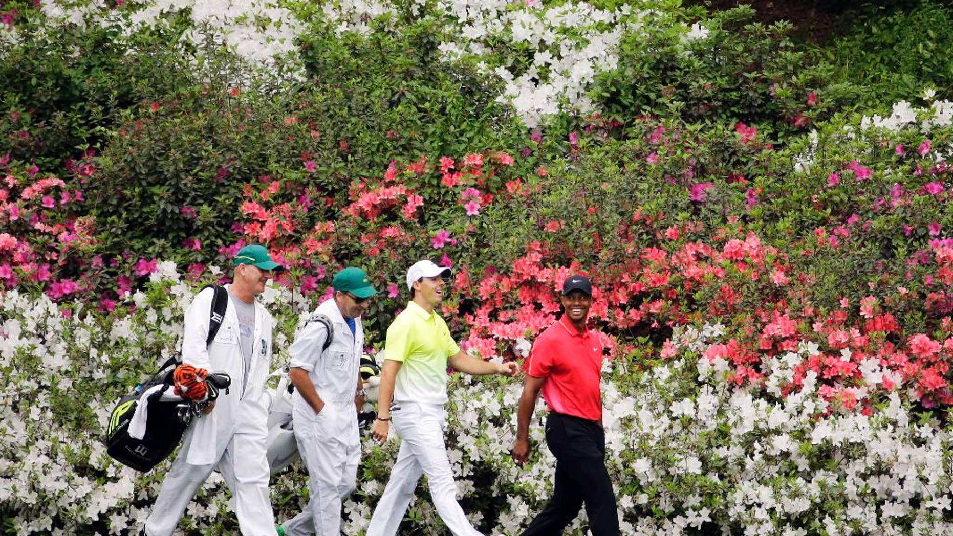 Tiger Woods, right, walks with Rory McIlroy, of Northern Ireland, and their caddies along the 13th fairway during the fourth round of the Masters golf tournament Sunday, April 12, 2015, in Augusta, Ga. (AP Photo/Matt Slocum)