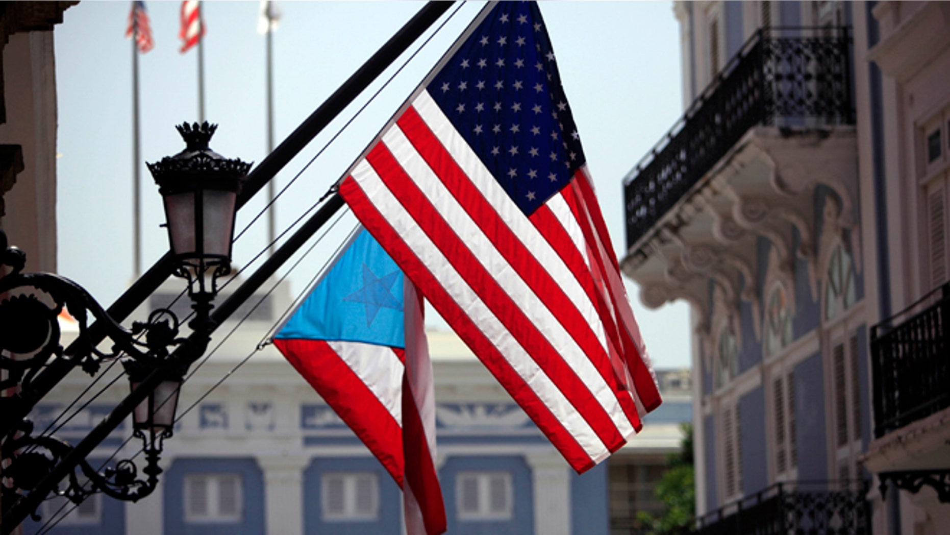 FILE - In this June 29, 2015 file photo, U.S. and Puerto Rico flags hang outside the governors mansion in Old San Juan, Puerto Rico. Puerto Rico is entering its ninth year of recession and is struggling with billions in public debt that Gov. Alejandro Garcia Padilla has said is unpayable given the current economic conditions. (AP Photo/Ricardo Arduengo, File)