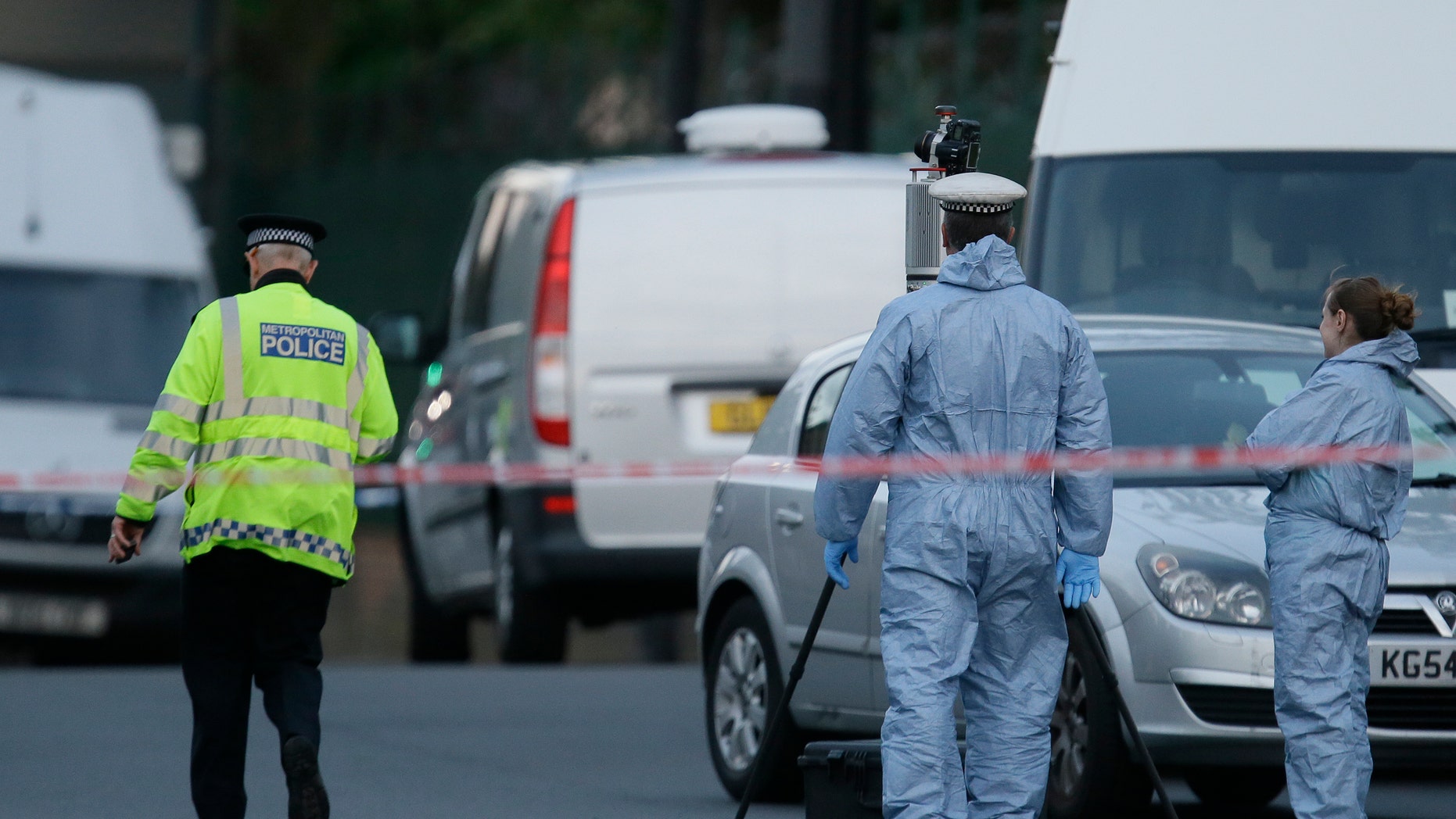 Police and forensic officers near the scene of an attack which has left one man confirmed dead and two people wounded near Woolwich barracks in London Wednesday, May, 22, 2013. Scotland Yard said officers responded to reports of an assault Wednesday afternoon in the London neighbourhood of Woolwich. London Ambulance service said one man was found dead at the scene and two other men were taken to the hospital, with one in serious condition.(AP Photo/Alastair Grant)