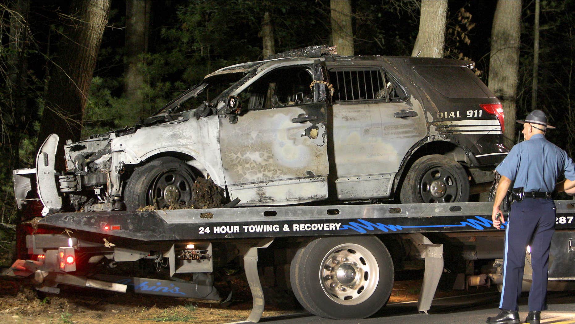 Sept. 2, 2015: A police officer watches as a cruiser that was shot at is removed from Forest Road
