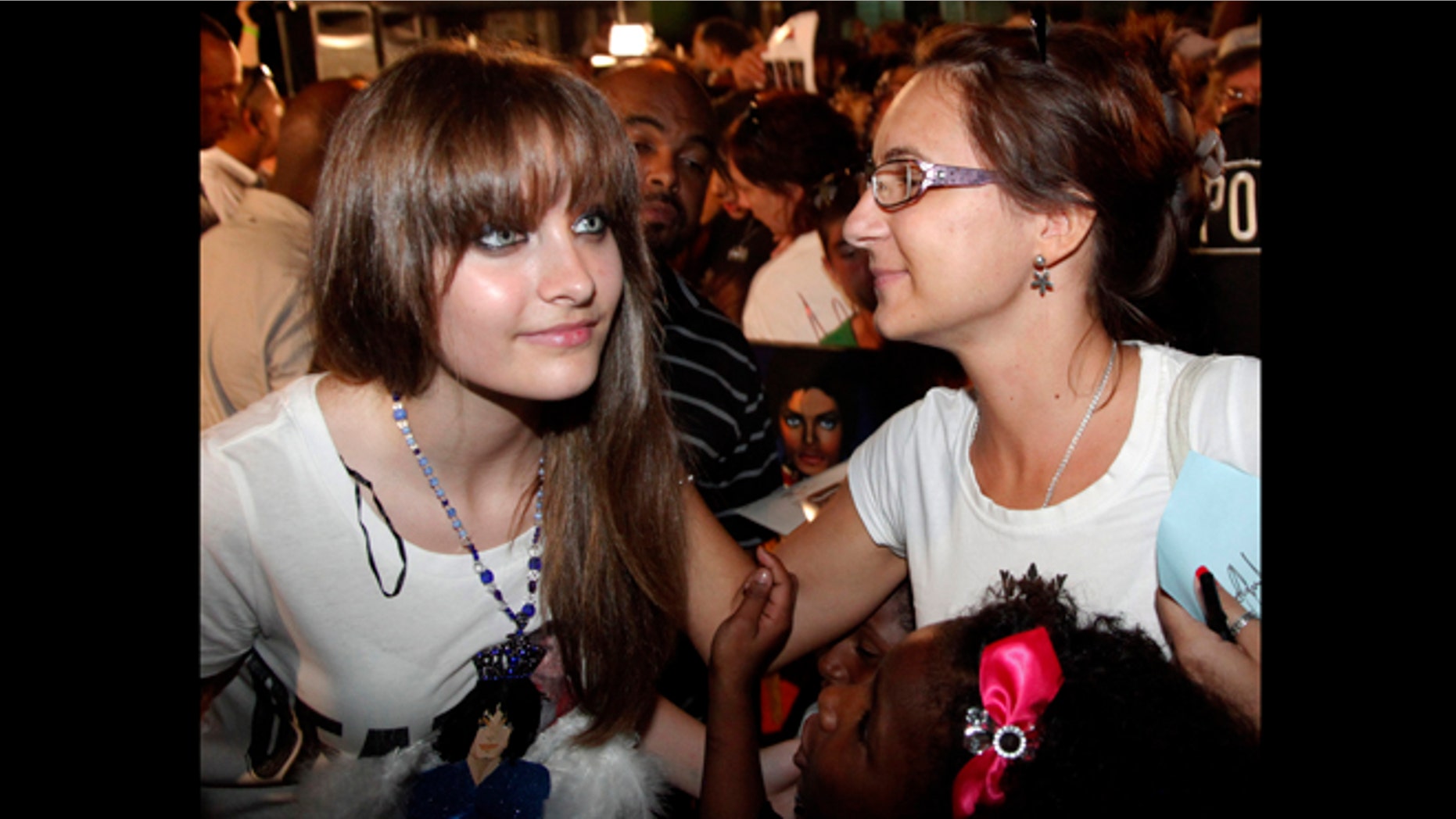 FILE - This Aug. 29, 2012 file photo shows Paris Jackson, left, daughter of the late pop icon Michael Jackson, poses with a fan outside Jackson's boyhood home during a celebration on what would have been Jackson's 54th birthday in Gary, Ind. Jackson is physically fine after being taken to a hospital early Wednesday, June 5, 2013, an attorney for Jackson's mother said. Perry Sanders Jr. writes in a statement that Paris Jackson is getting appropriate medical attention and the family is seeking privacy.