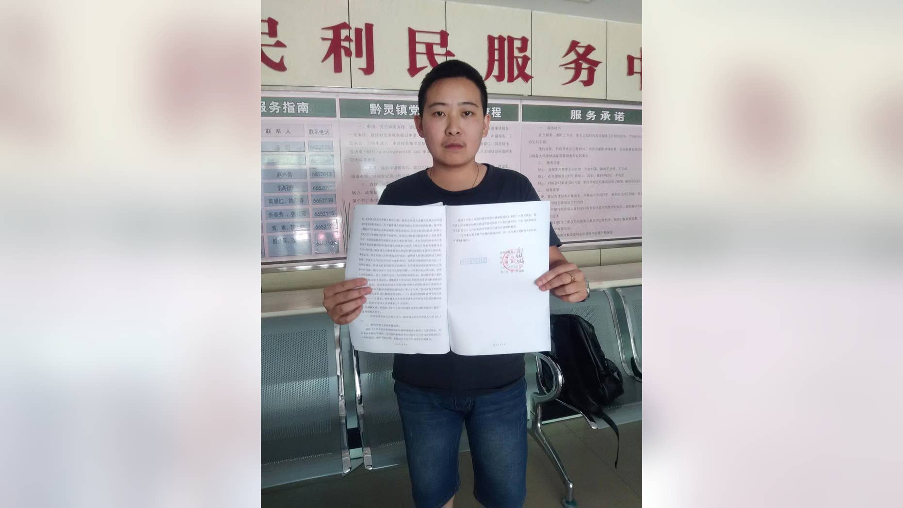 In this photo released by Mr. C, a transgender man who uses the name Mr. C to protect his parents from discrimination, holds up the arbitration results while posing for a photo at a government office in Guiyang in southwestern China's Guizhou province Tuesday, May 10, 2016. Mr. C said he was disappointed but will continue to fight for equality after a labor arbitration panel on Tuesday, rejected his complaint that he was fired unfairly, in China's first transgender job discrimination case. (Mr. C via AP)
