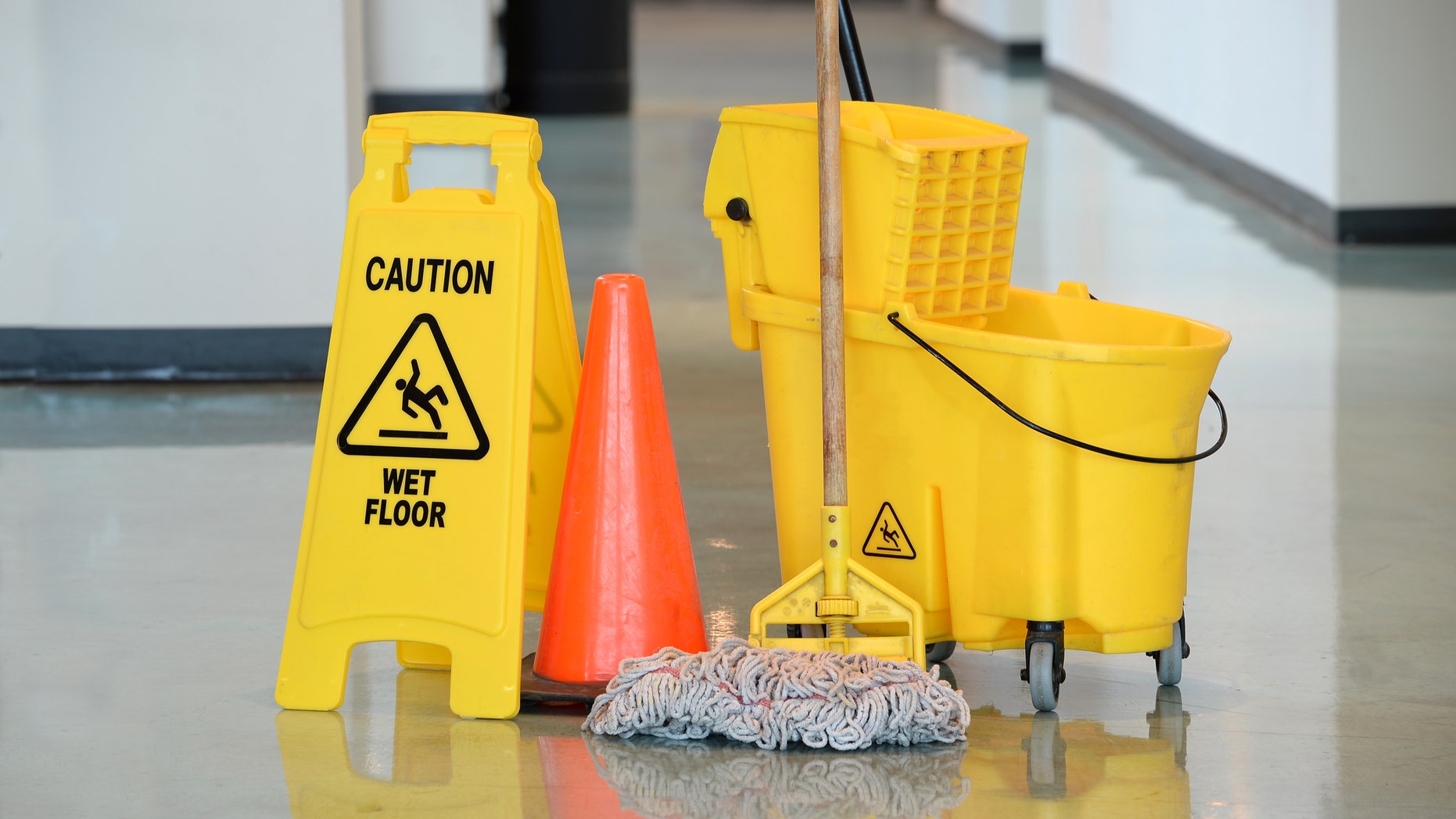 Caution sign with mop and bucket on office floor
