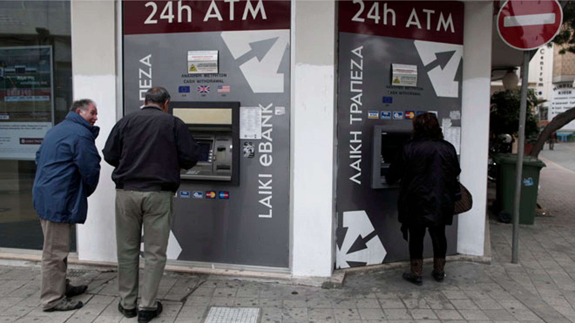 March 19, 2013: Cypriots use the ATM machines outside of a closed Laiki Bank branch in capital Nicosia, Cyprus. Cypriot finance officials are revising a planned financial bailout to relieve small account holders from having to pay a charge on their savings in order to secure an international rescue of the country's troubled banks.