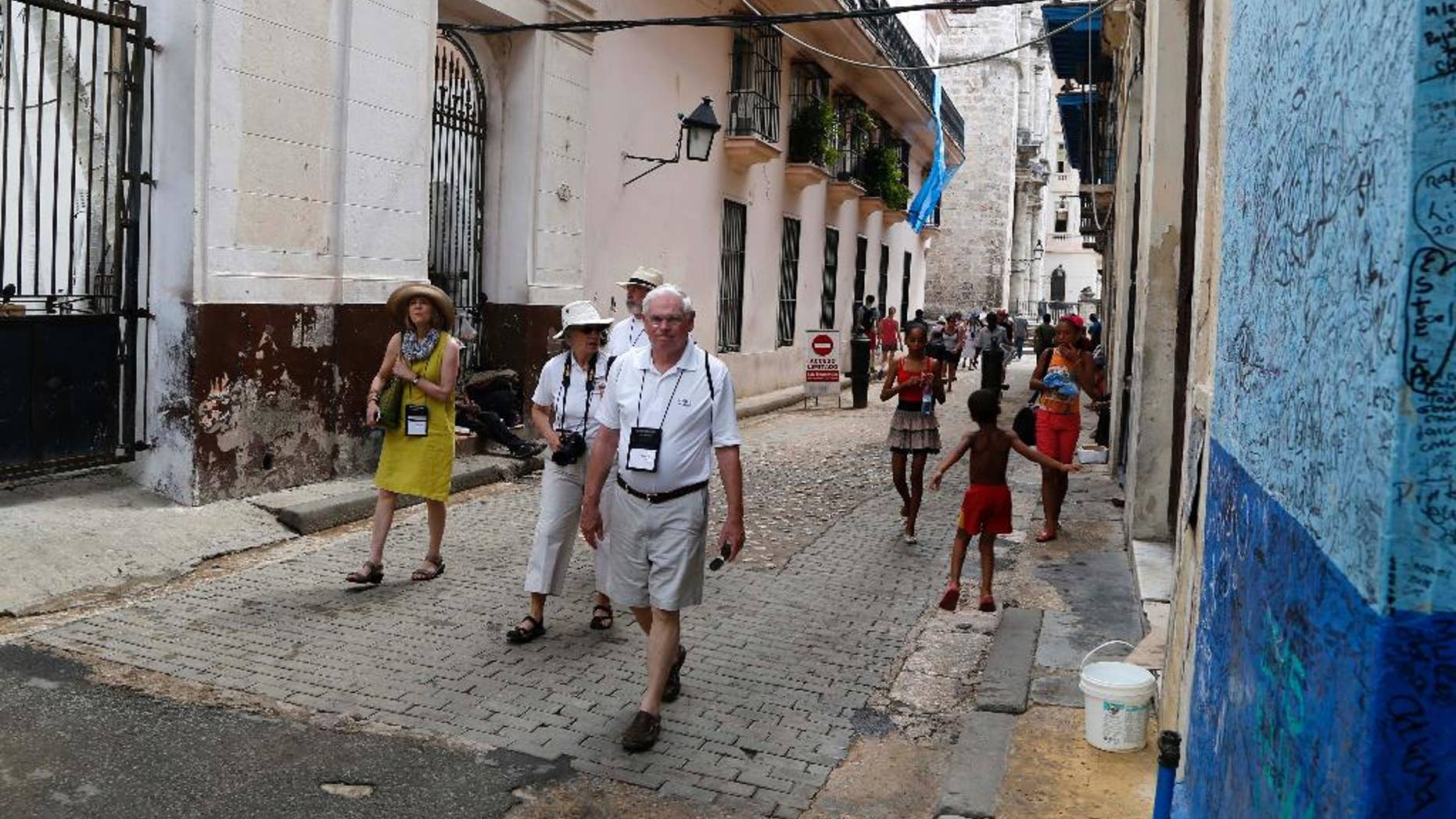 FILE - In this May 24, 2015 file photo, US tourists walks outside the Bodeguita del Medio Bar frequented by the late American novelist Ernest Hemingway in Old Havana, Cuba. Cuba's official news media announced on Thursday, July 7, 2016 the number of American travelers to the island is up 83.9 percent for the first half of the year, compared with the same January-June period in 2015. Prensa Latina reported that there were also significant increases in visitors from nations such as Spain, Italy, Poland and Germany. (AP Photo/Desmond Boylan File)