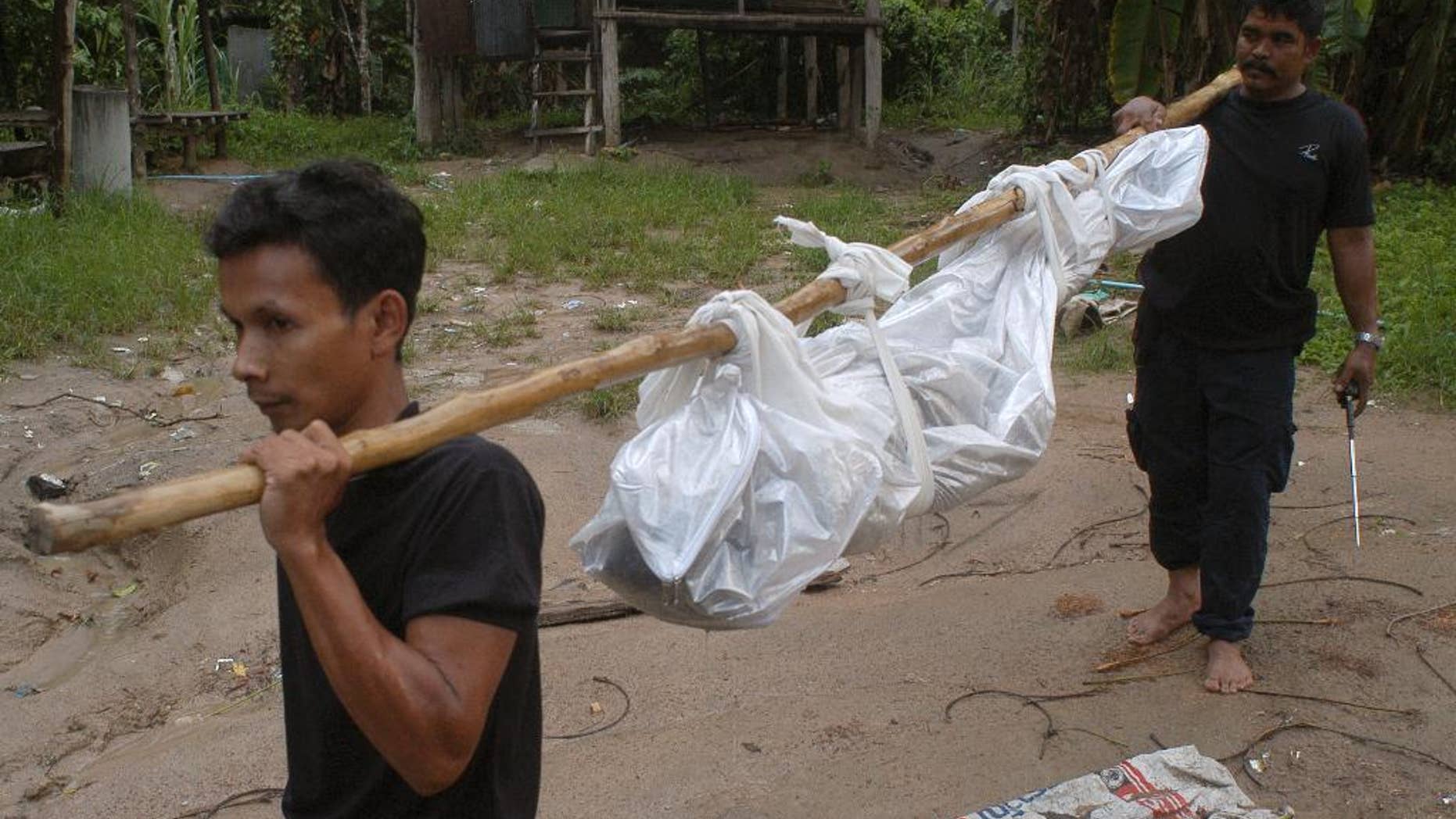 Thai police officials measure a shallow grave in Padang Besar, Songkhla province, southern Thailand, Saturday, May 2, 2015. Police officials in Thailand trekked into the mountains to dig up shallow graves Saturday, after the grim discovery of an abandoned jungle camp renewed calls for a crackdown on the human trafficking networks operating in the Southeast Asian country. (AP Photo/Sumeth Panpetch)