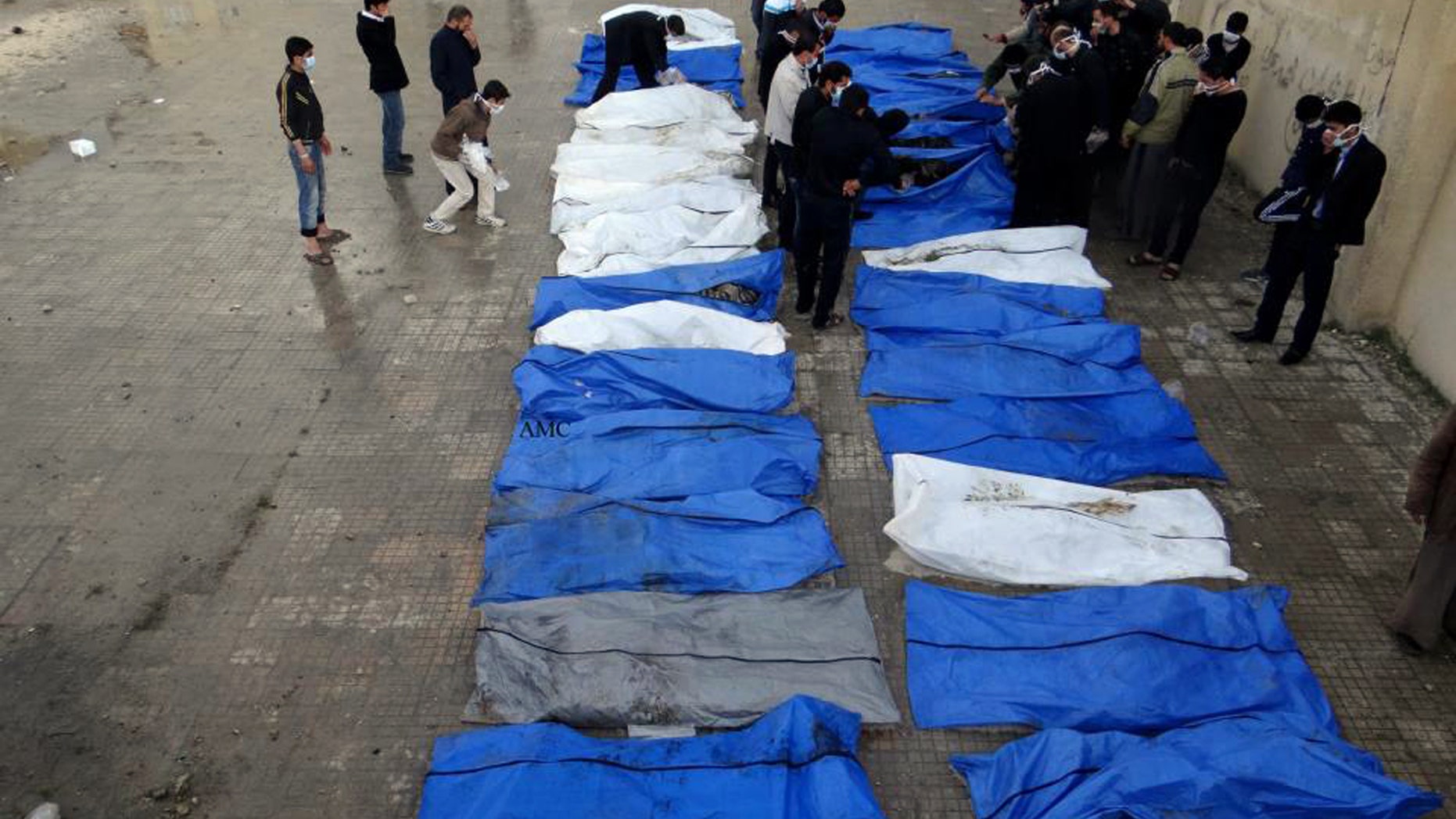 This citizen journalism image provided by Aleppo Media Center AMC which has been authenticated based on its contents and other AP reporting, shows Syrians standing next to the bodies of Syrians that have been killed by Syrian Army snipers, in Aleppo, Syria, Tuesday, April. 16, 2013. The Syrian Red Crescent recovered 31 bodies between the Aleppo neighborhoods of Sakhour and Midan, according to the Aleppo Media Center activist group. The Syrian Observatory for Human Rights also reported the discovery of 31 bodies in the same location. Both groups said the dead had been killed by snipers in recent months, but because of the location of the bodies they couldn’t be retrieved for burial until now. (AP Photo/Aleppo Media Center AMC)