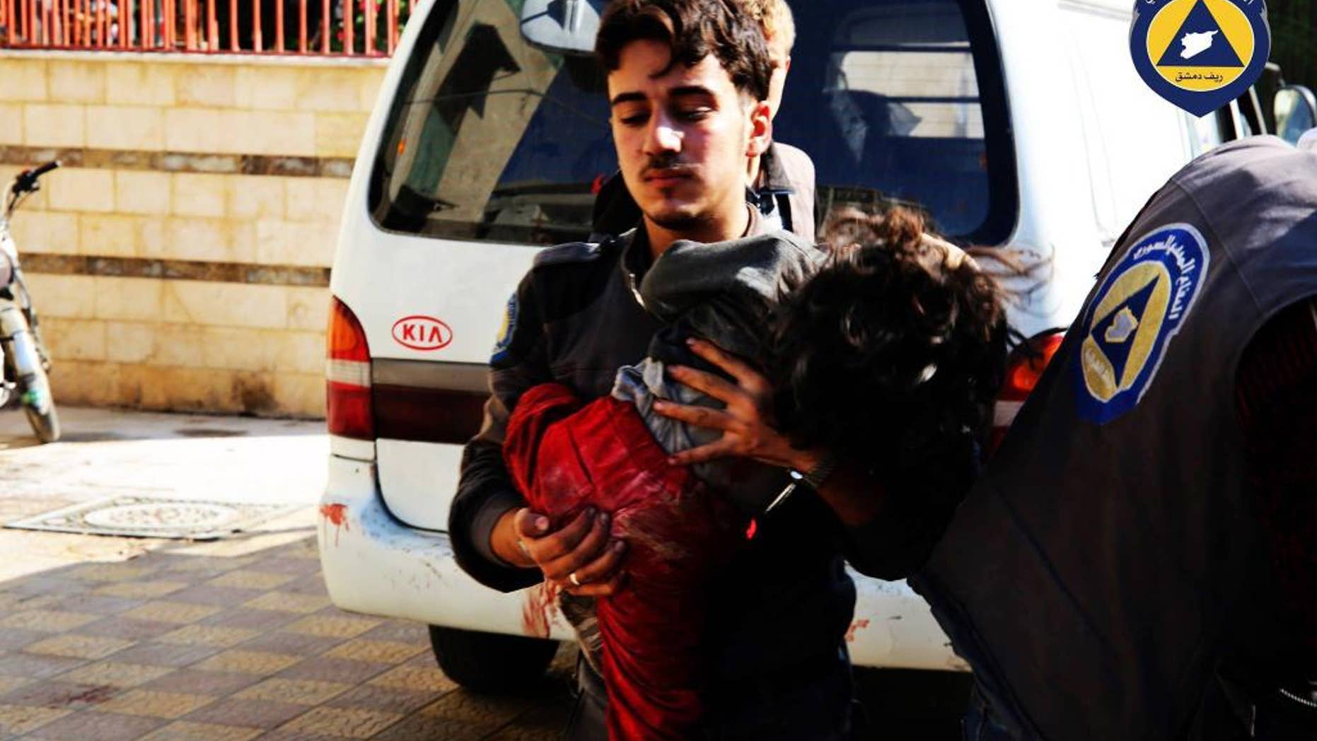 This photo provided by the Syrian anti-government activist group Syrian Civil Defense, shows a paramedic holding a child after witnesses said a market was hit by Syrian government forces in Douma, Syria, Friday, Oct. 30, 2015. (Syrian Civil Defense via AP)