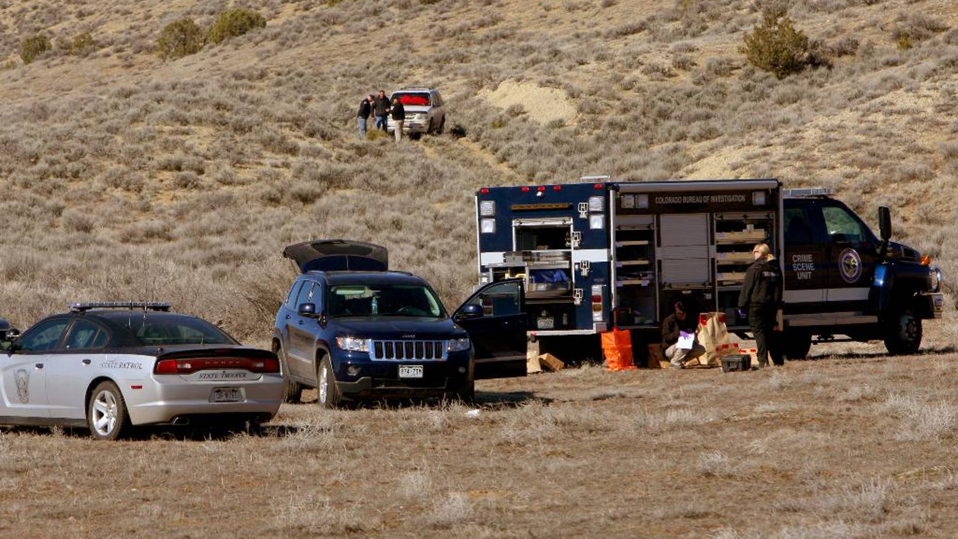 In this March 10, 2015 photo, members of the Judicial District's critical incident team investigate an officer-involved shooting east of Dinosaur, Colo. A Colorado sheriff's deputy and a state wildlife officer were held hostage by a man and a woman before a struggle erupted and the man was fatally shot, authorities said. Neither the deputy nor the wildlife officer was injured in the confrontation Monday. (AP Photo/The Deseret News, Geoff Liesik)