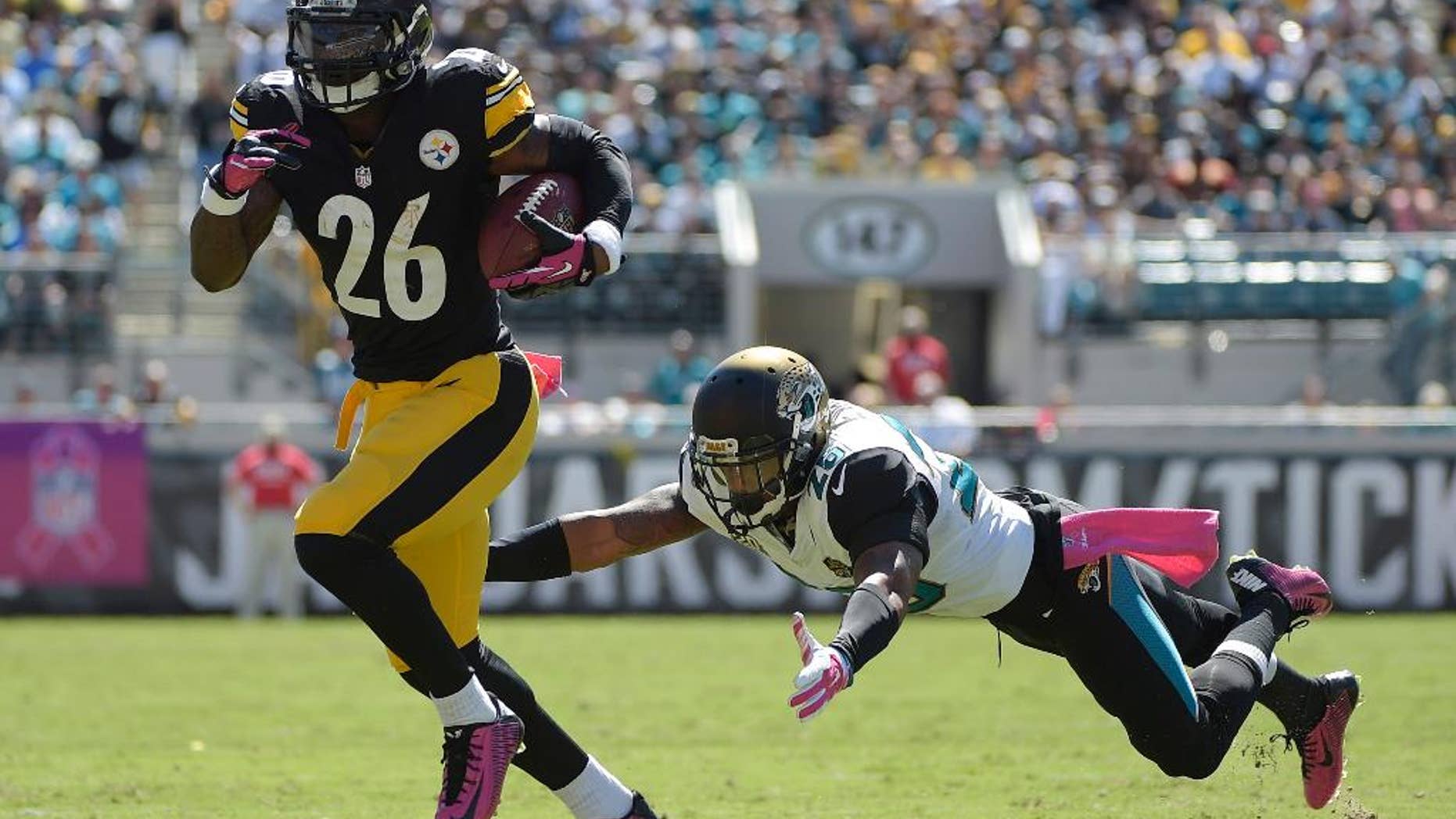 Pittsburgh Steelers running back Le'Veon Bell (26) breaks away from Jacksonville Jaguars strong safety Josh Evans, right, for yardage during the first half of an NFL football game in Jacksonville, Fla., Sunday, Oct. 5, 2014. (AP Photo/Phelan M. Ebenhack)