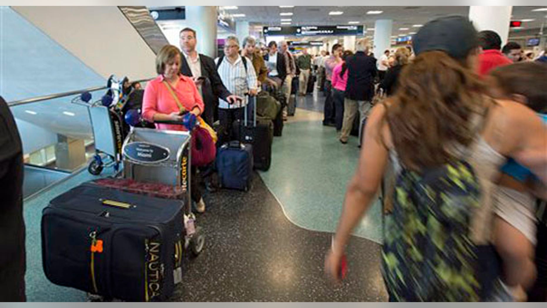 People stand in long lines at the American Airlines ticketing counter at Miami International Airport, Tuesday, April 16, 2013 as they try to make arrangements for new flights.