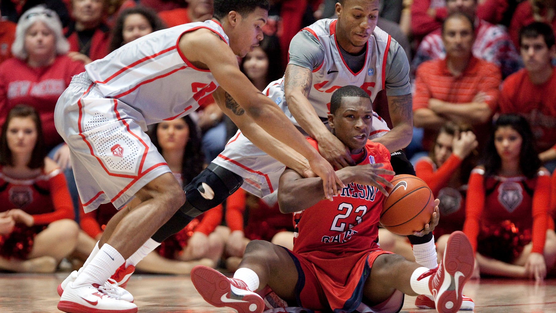 Fresno State's Marvelle Harris (23) hits the floor to recover a loose ball while pressured by New Mexico's Cleveland Thomas, left, and Chad Adams during the first half of an NCAA college basketball game on Saturday, Jan. 12, 2013, in Albuquerque, N.M. (AP Photo/Eric Draper)