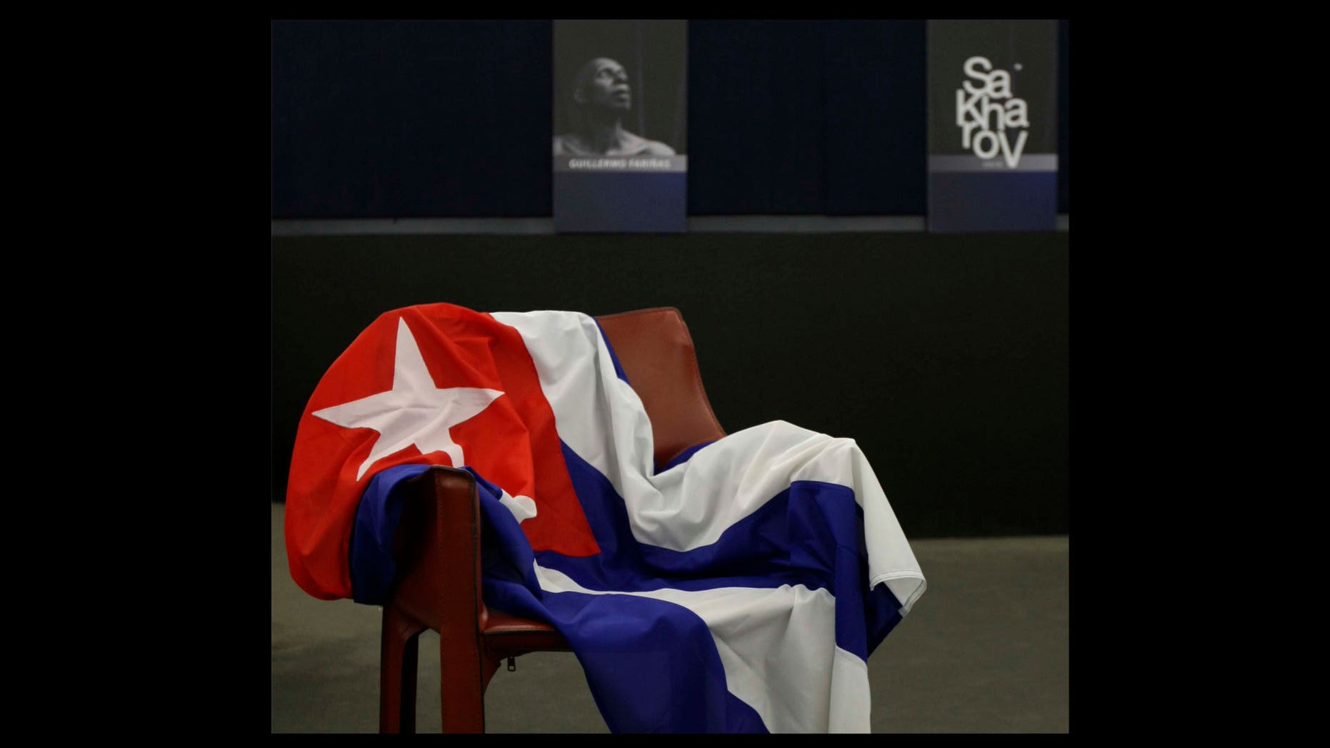 An empty chair bearing the Cuban flag and representing Cuban dissident Guillermo Farinas, is seen before European Parliament president Jerzy Buzek, back right, awarded The Sakharov Prize for Freedom of Thought to Farinas in his absence, at the European Parliament in Strasbourg, eastern France, Wednesday, Dec. 15, 2010. The European Union parliament has criticized Cuba for not allowing a dissident protester to travel to collect its biggest human rights award. (AP Photo/Christian Lutz)