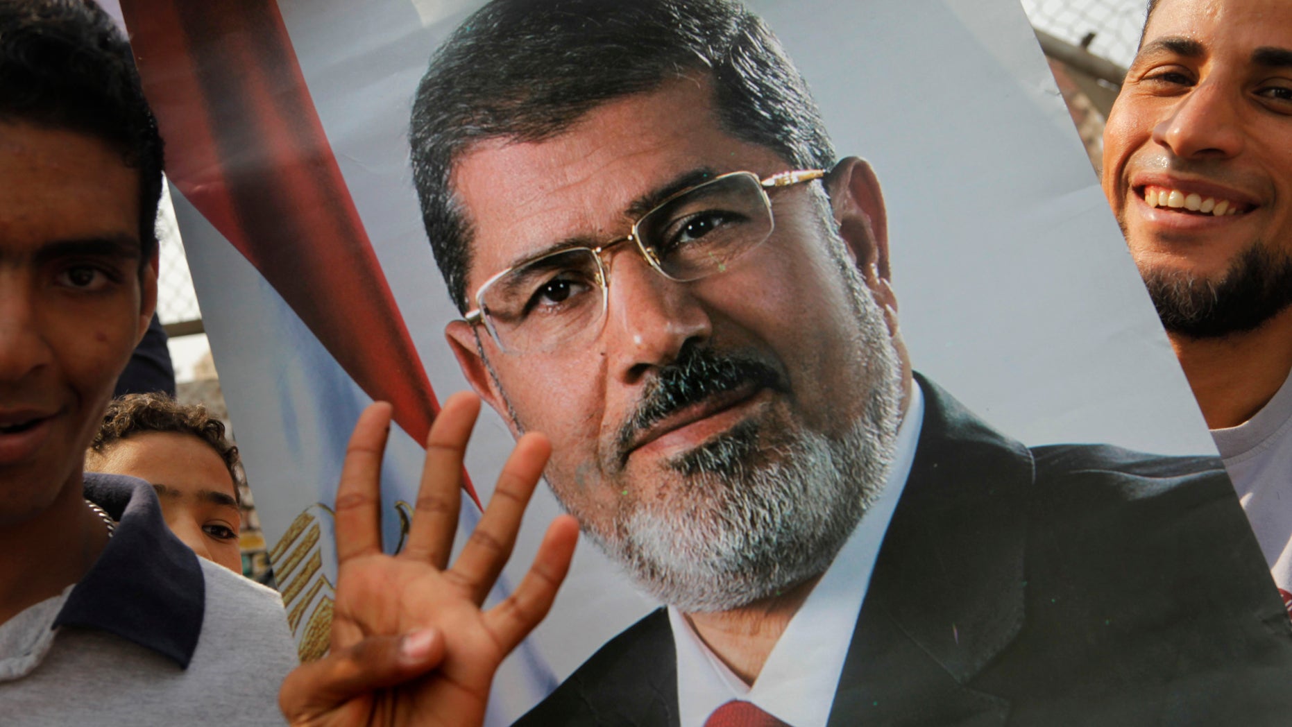 Supporters of Egypt's ousted President Mohammed Morsi raise his poster and a hand with four raised fingers, which has become a symbol of the Rabaah al-Adawiya mosque, where Morsi supporters had held a sit-in for weeks that was violently dispersed in August, during a protest in Cairo, Egypt, Friday, Nov. 8, 2013. (AP Photo/Amr Nabil)