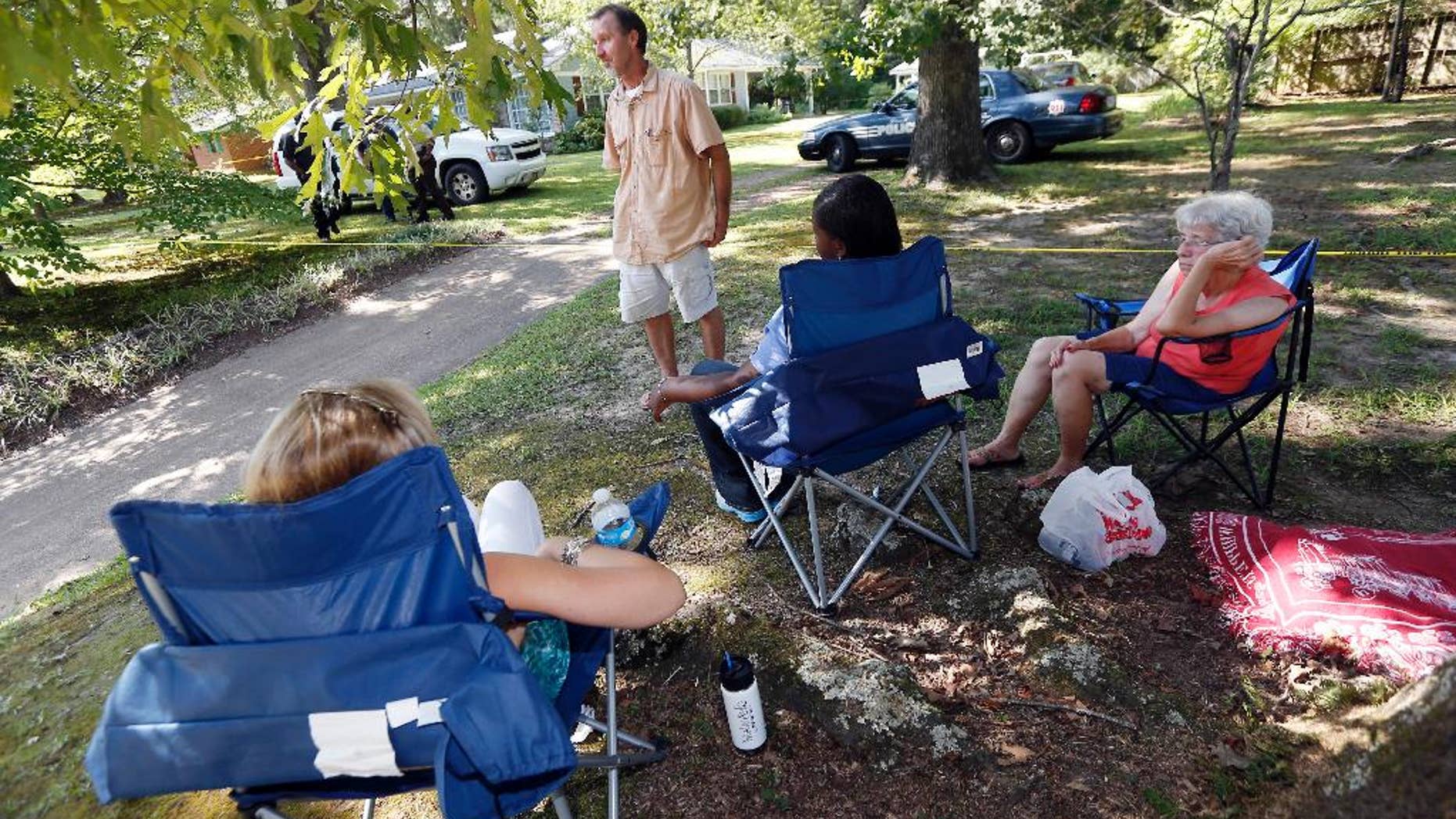 Sam Sample, a parishioner of St. Thomas Catholic Church in Lexington, Miss., background, paces while other church members and neighbors watch investigators at the house in the background where two nuns who worked as nurses lived in Durant, Miss., Thursday, Aug. 25, 2016. The nuns were found slain in their home, and there were signs of a break-in and their vehicle was missing, officials said Thursday. (AP Photo/Rogelio V. Solis)