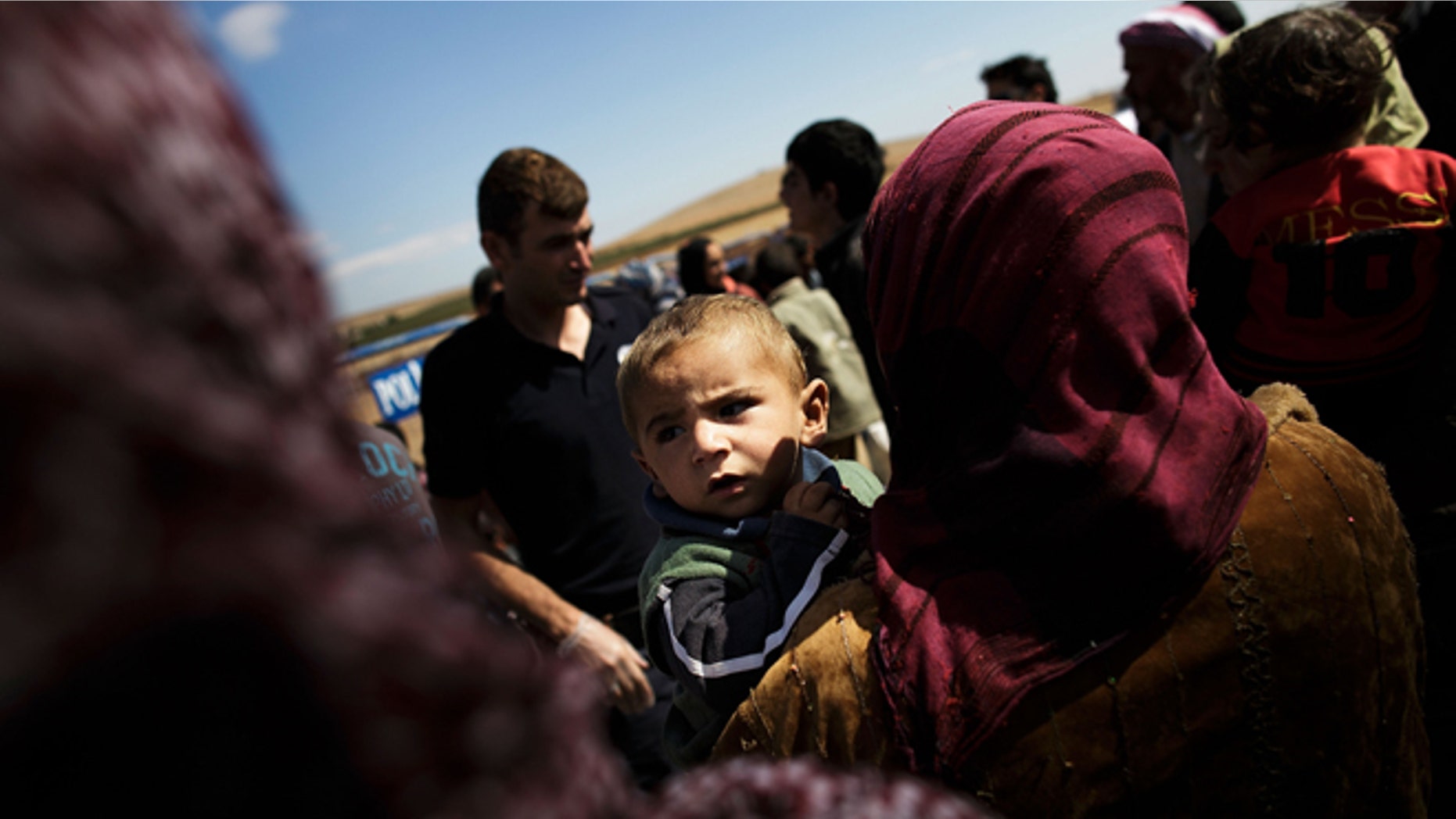 SANLIURFA, TURKEY - SEPTEMBER 30: A woman holds a boy as refugees cross the border from Syria into Turkey September 30, 2014 near Suruc, Turkey. (Photo by Carsten Koall/Getty Images)