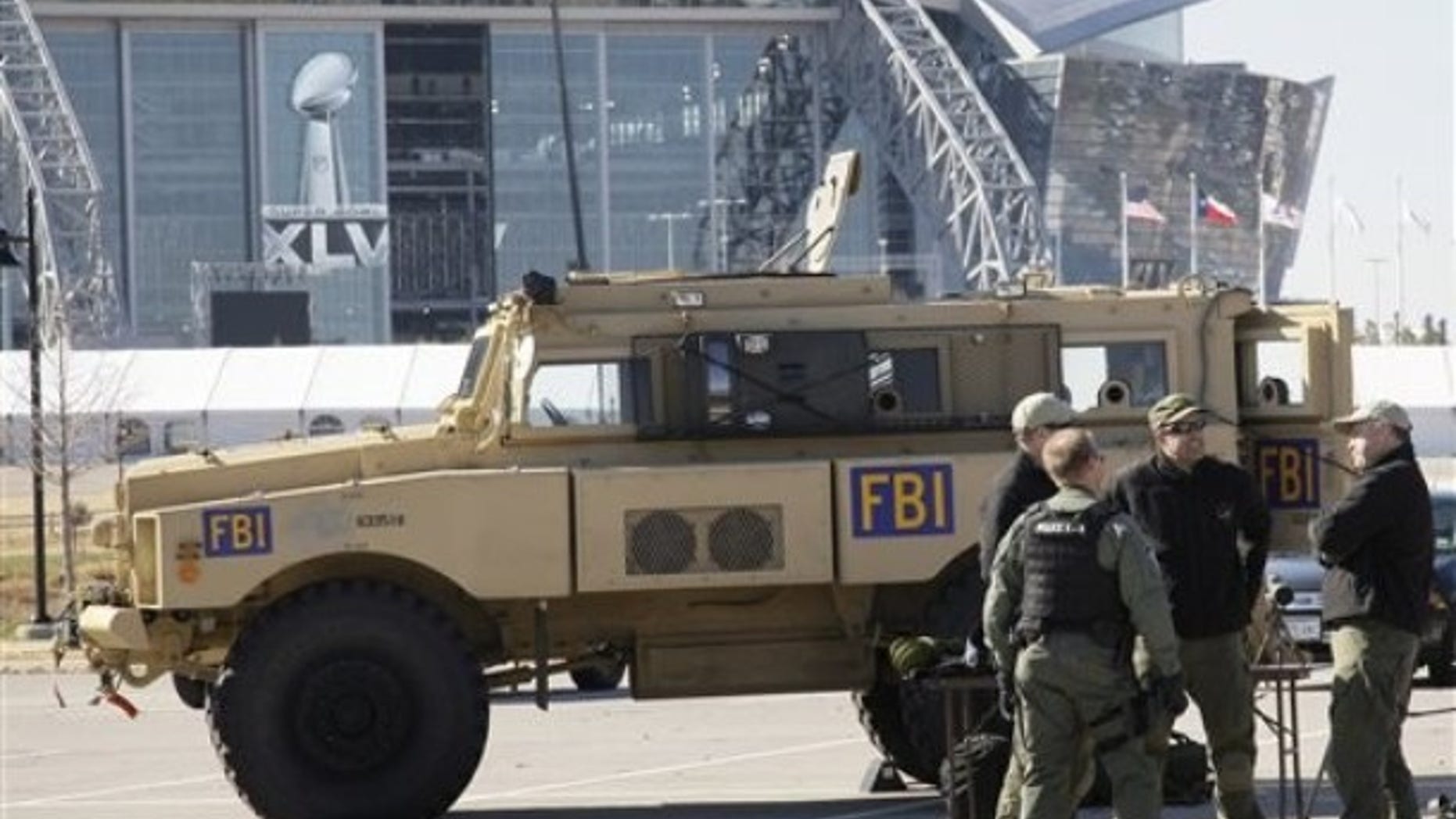 Cowboys Stadium is seen at rear as members of the FBI stand by one of their assault vehicles during a media day event where public safety agencies, local, state and federal, showed some of the equipment and tools being used to protect the public for the upcoming Super Bowl XLV NFL football game, Friday, Jan. 21, 2011, in Arlington, Texas. (AP)