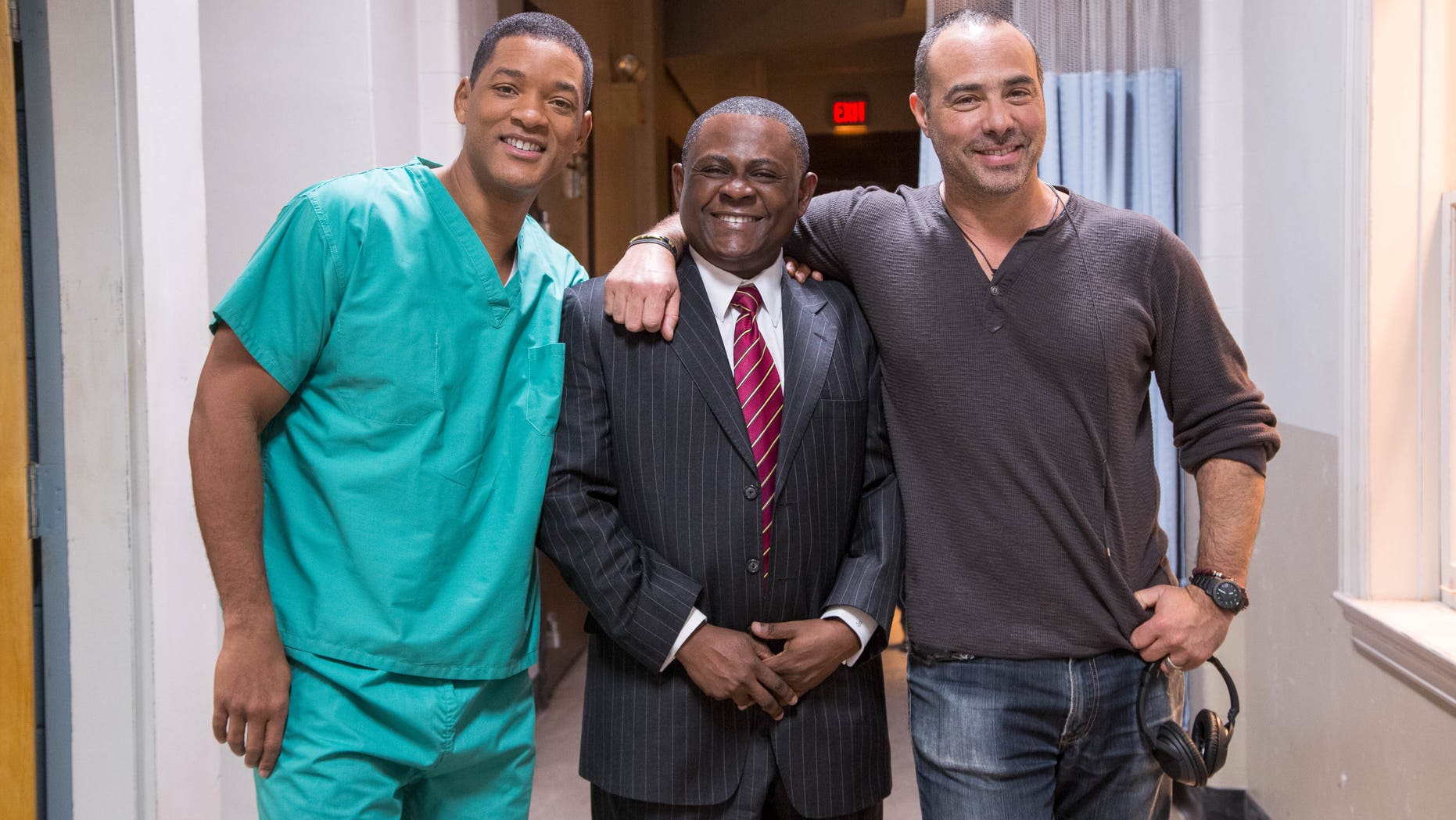 This image released by Columbia Pictures shows, from left, Will Smith, Dr. Bennet Omalu and director Peter Landesman on the set of the film, "Concussion." Smith plays Omalu, a Nigerian-born forensic pathologist in Pittsburgh who knows nothing about football when he performs the autopsy on former Steelers center Mike Webster. Omalu discovers CTE in Webster's brain, setting him on a journey that exposes the concussion crisis. (Melinda Sue Gordon/Columbia Pictures via AP)