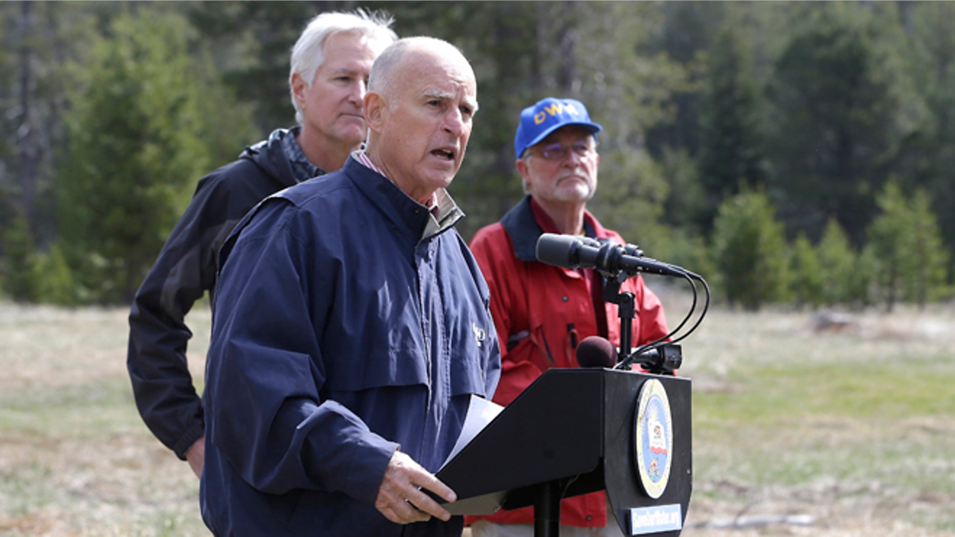 April 1, 2015: Gov. Jerry Brown, center, answers a question concerning the executive order he signed requiring the state water board to implement measures in cities and towns to cut water usage by 25 percent compared with 2013 levels, at Echo Summit, Calif.