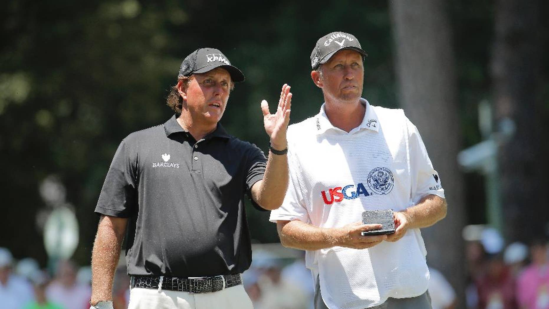 Phil Mickelson talks with his caddy on the third hole during the final round of the U.S. Open golf tournament in Pinehurst, N.C., Sunday, June 15, 2014. (AP Photo/Matt York)