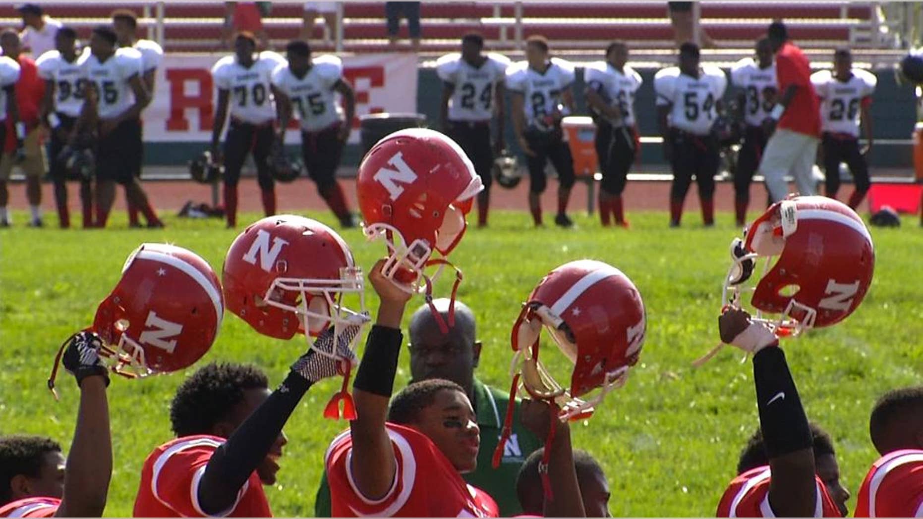 In this image taken from video on Saturday, Aug. 23, 2014, Normandy High School football players, students and parents observe a moment of silence for Michael Brown before the start of the first game of the school year, in Ferguson, Mo. Brown, 18, was killed by a Ferguson police officer on Aug. 9, eight days after he graduated from the high school. (AP Photo/Alex Sanz)