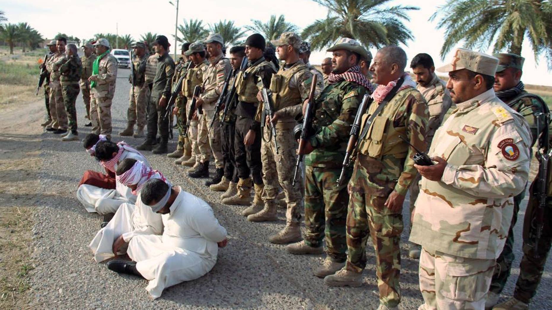 FILE - In this file photo taken Thursday, May 28, 2015, Iraq's Badr Brigades Shiite militia detain four men that they suspect of being militants of the Islamic State group outside the oil refinery in Beiji, some 155 miles (250 kilometers) north of Baghdad, Iraq. Iraqi troops backed by Shiite militias recaptured key parts of the northern refinery town of Beiji from Islamic State militants on Sunday, June 7, a general said. (AP Photo, File)